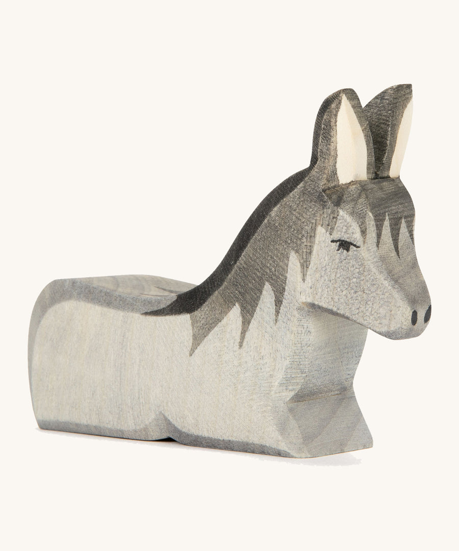 A grey wooden lying donkey on a cream background