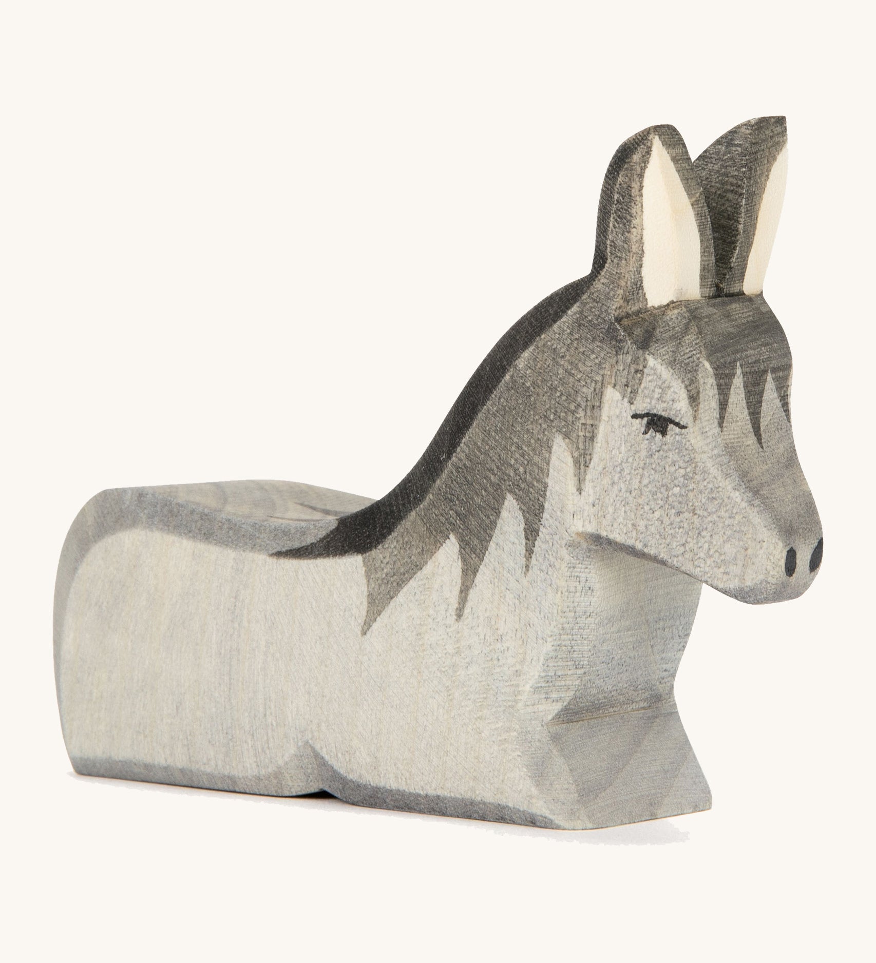 A grey wooden lying donkey on a cream background