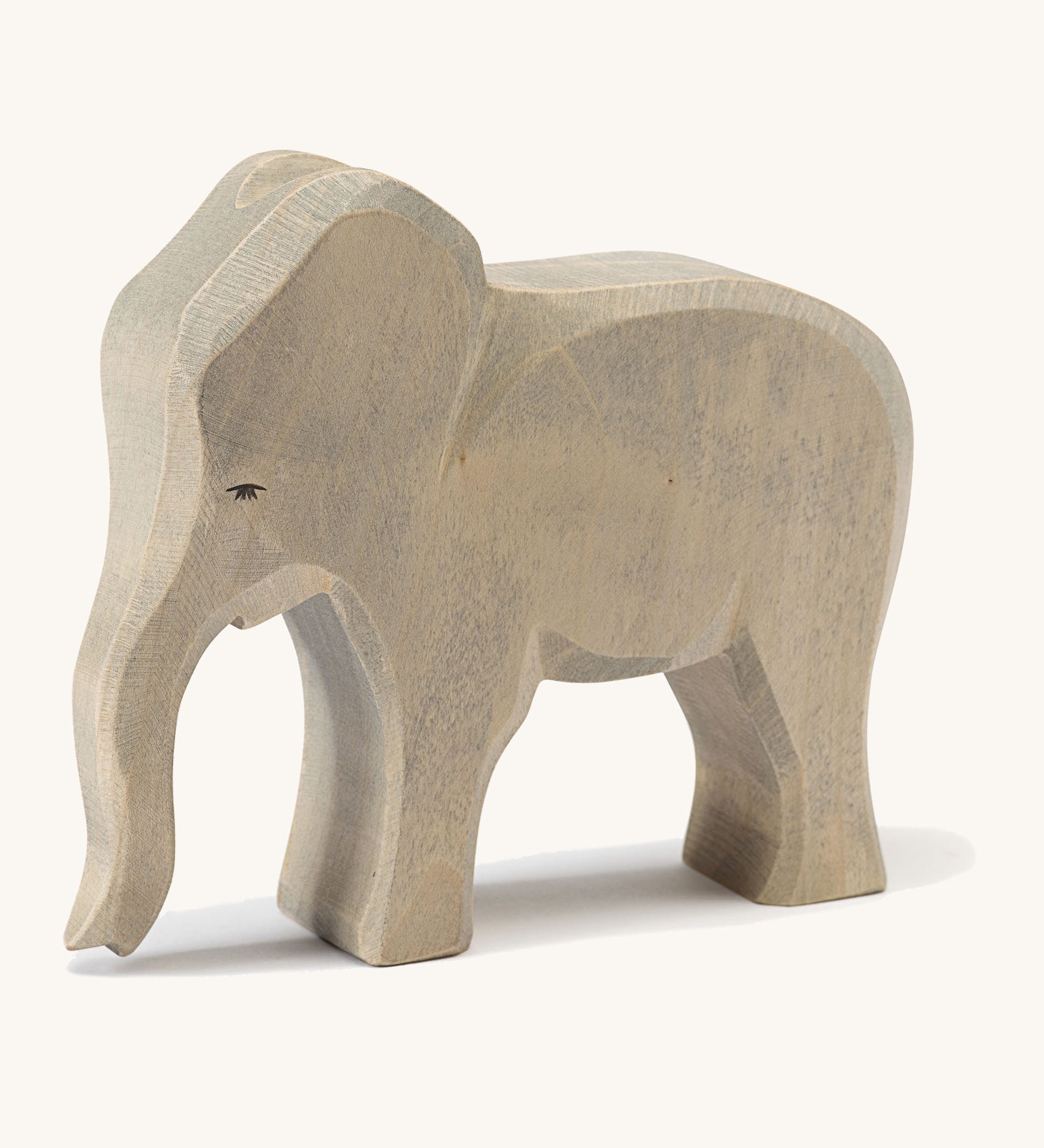 A wooden Ostheimer female elephant figure on a cream background.