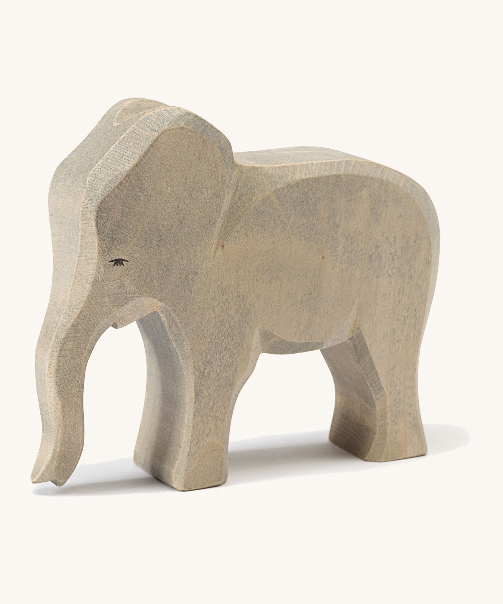 A wooden Ostheimer female elephant figure on a cream background.