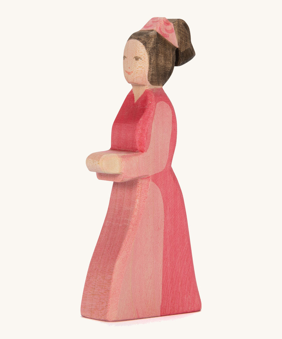 A pink lady in waiting wooden figure on a cream background