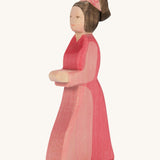 A pink lady in waiting wooden figure on a cream background