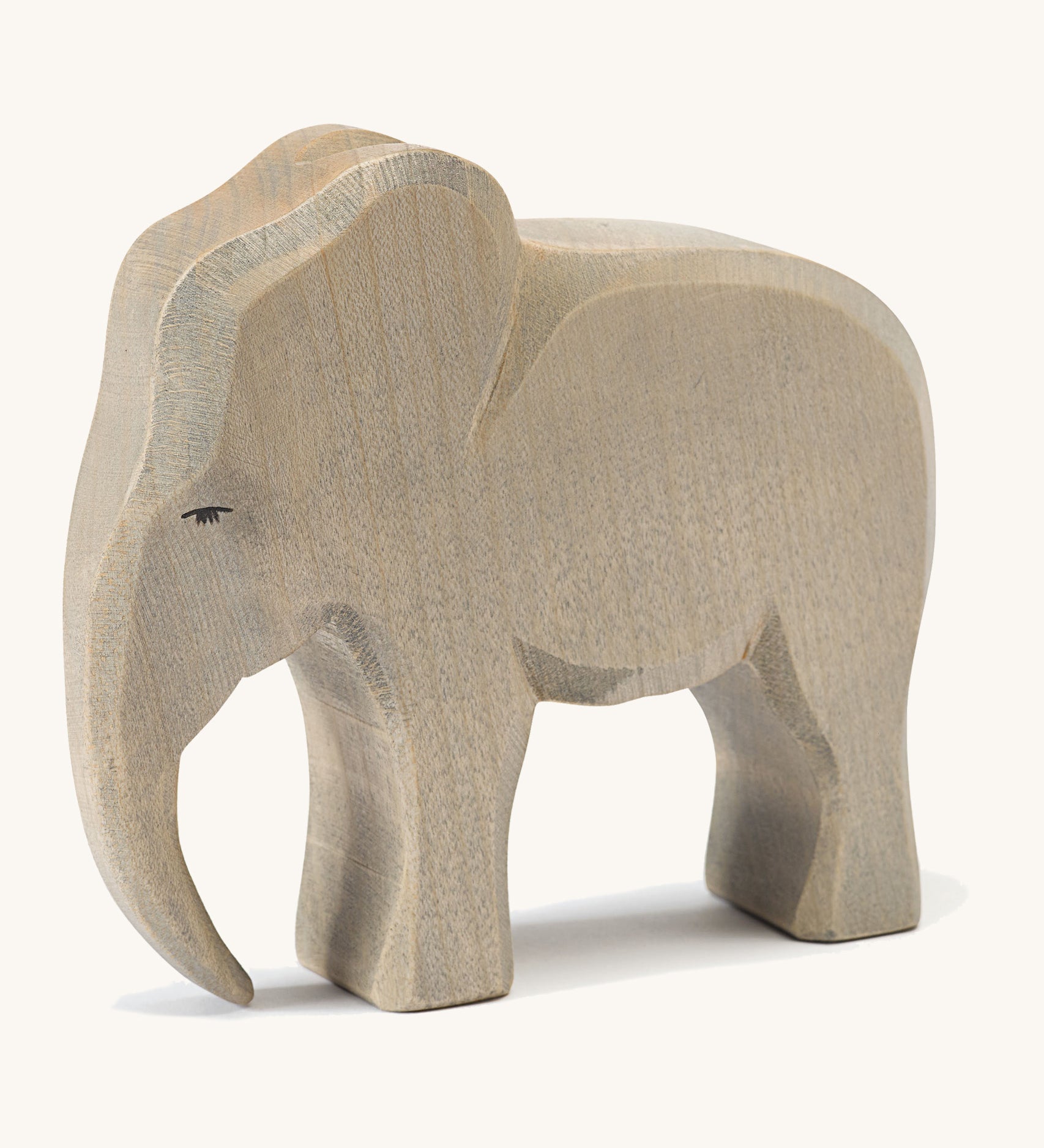 A wooden male Ostheimer elephant figure on a cream background.