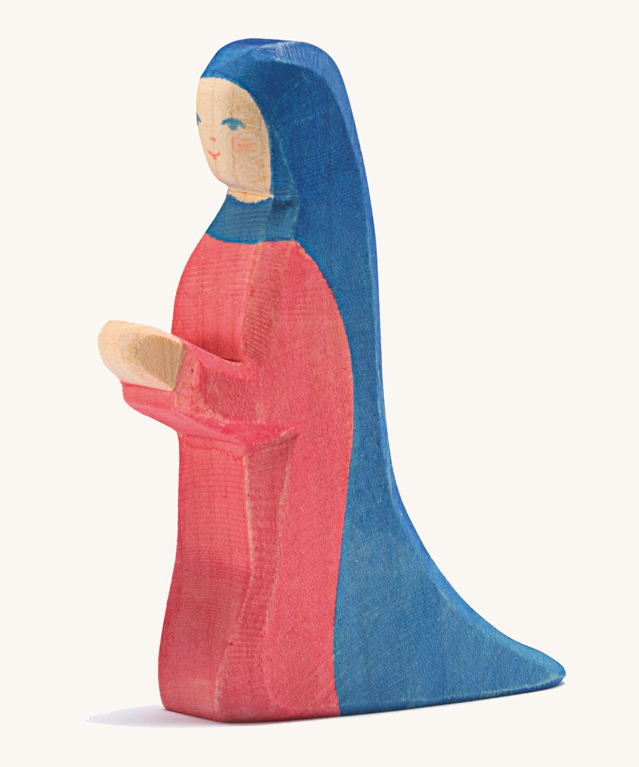 A wooden kneeling Mary figure on a cream background