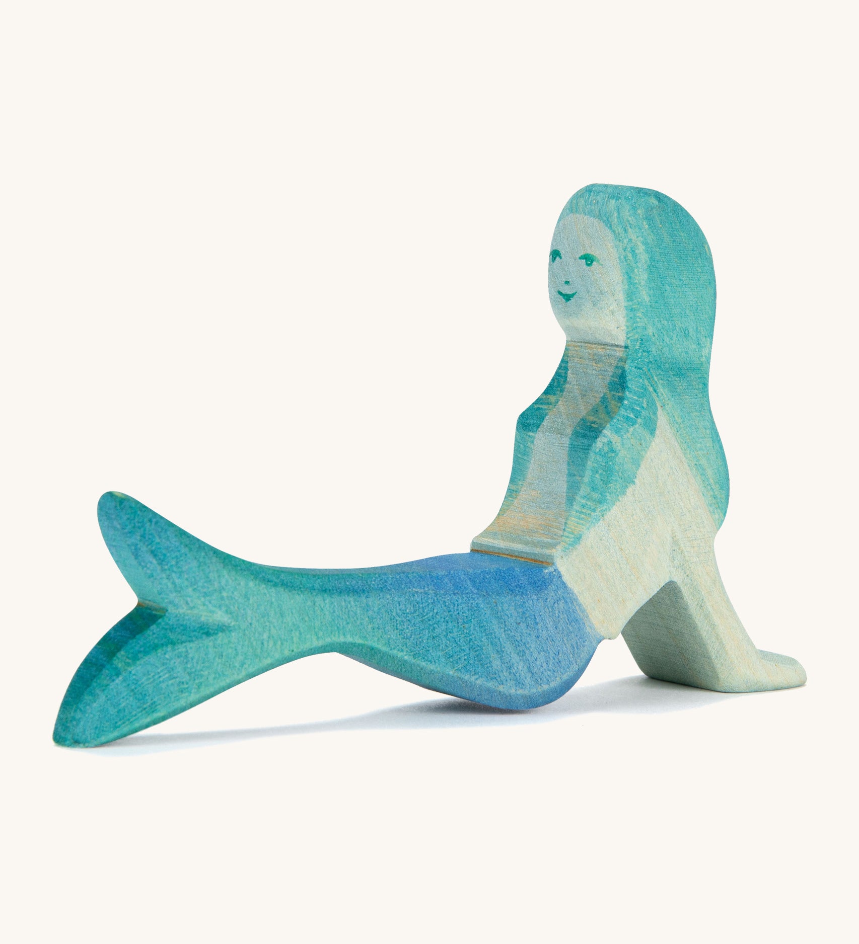 A wooden resting Ostheimer mermaid figure with blue hair on a cream background.