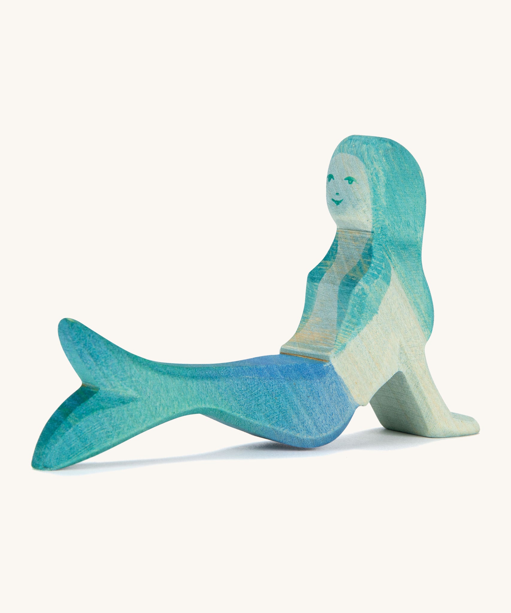 A wooden resting Ostheimer mermaid figure with blue hair on a cream background.