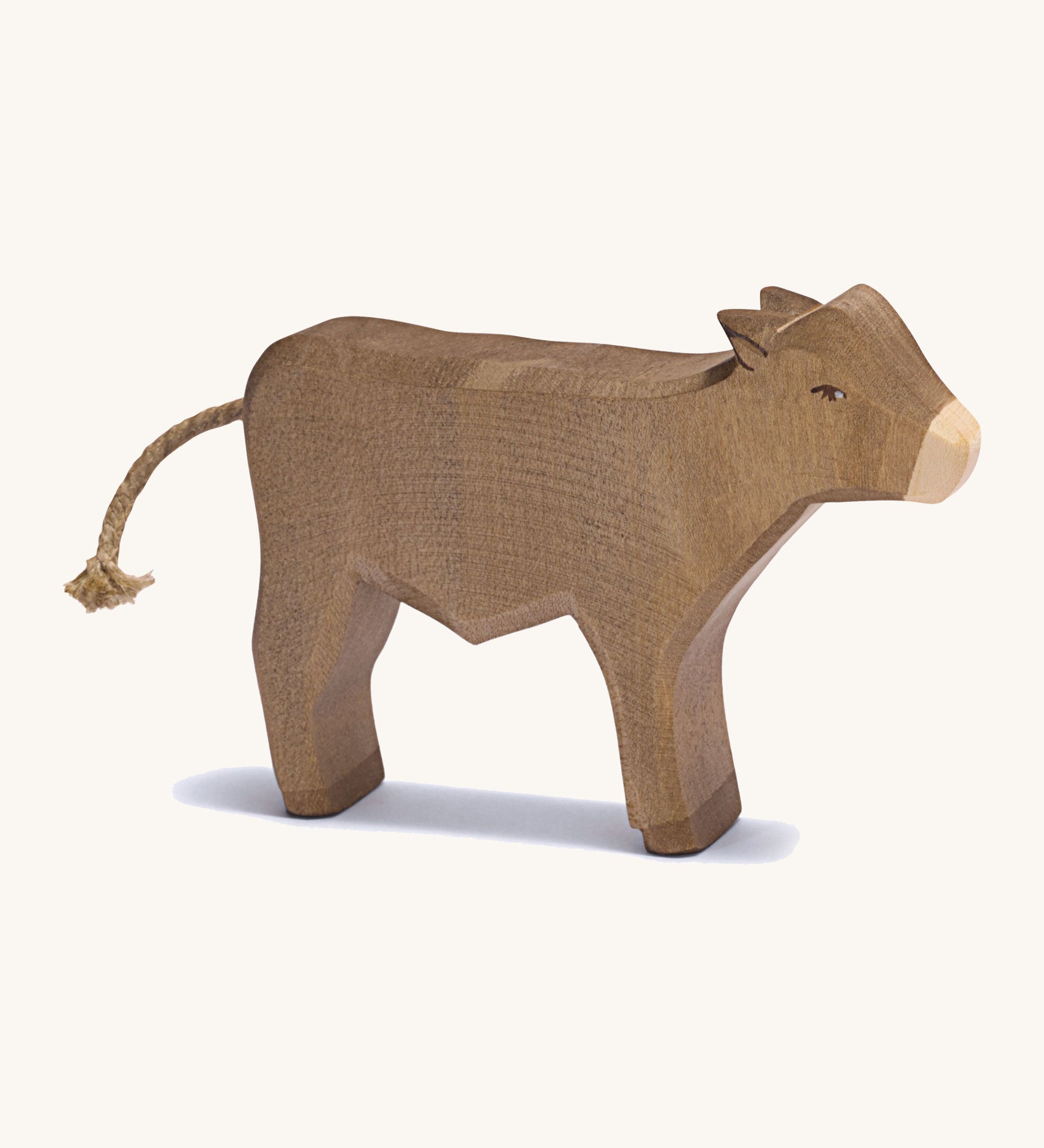 A brown standing wooden ox figure on a cream background