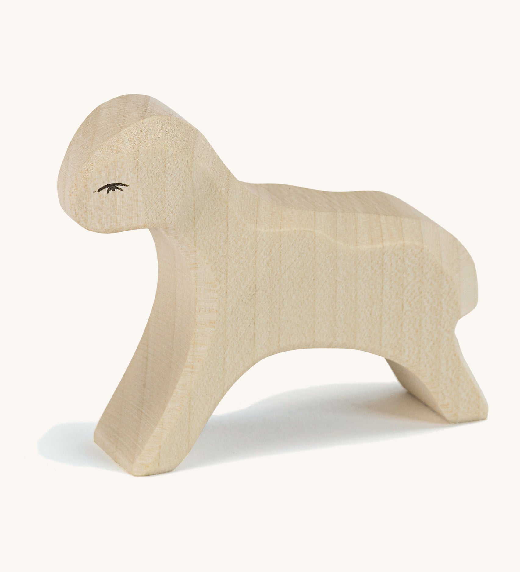 A white wooden Ostheimer running lamb figure on a cream background.