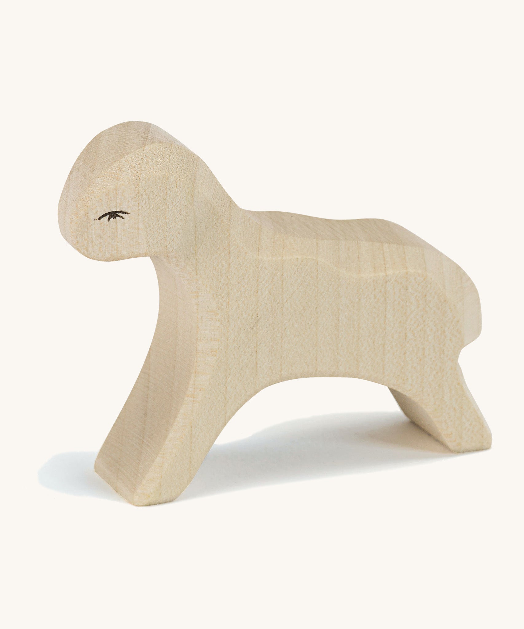 A white wooden Ostheimer running lamb figure on a cream background.