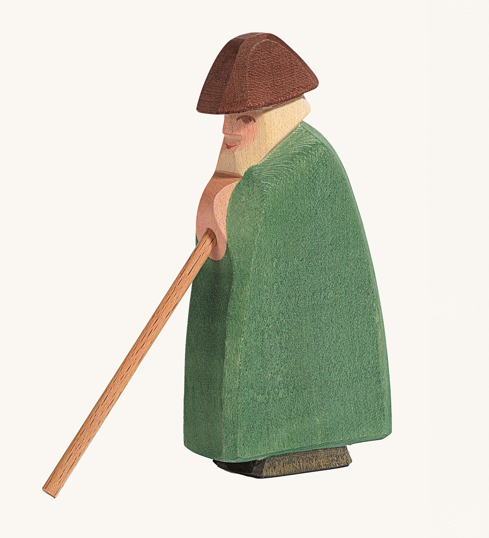 Ostheimer Shepherd With Staff wooden toy figure on a plain background. The shepherd is wearing green clothing with a brown hat. 