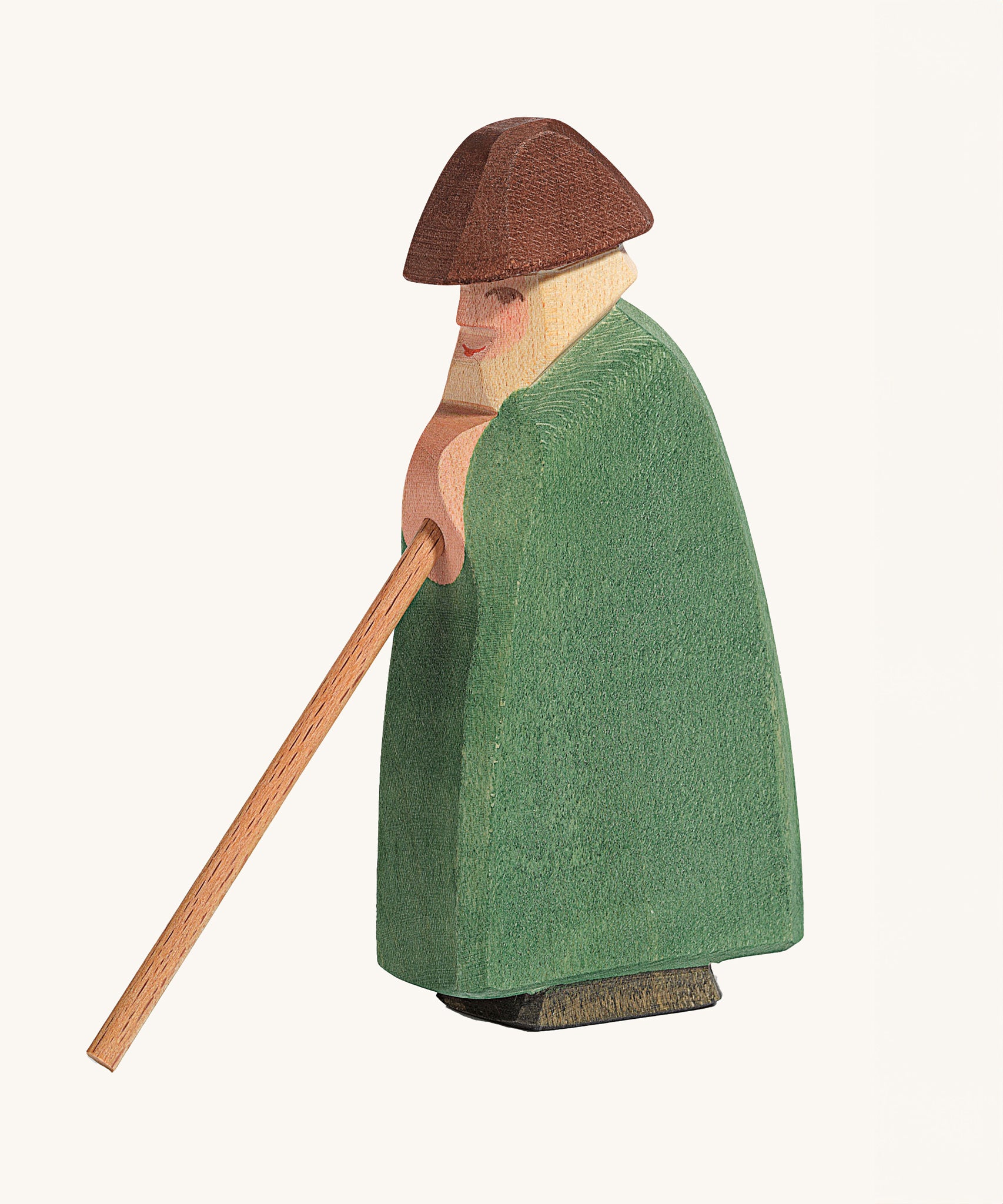 Ostheimer Shepherd With Staff wooden toy figure on a plain background. The shepherd is wearing green clothing with a brown hat. 