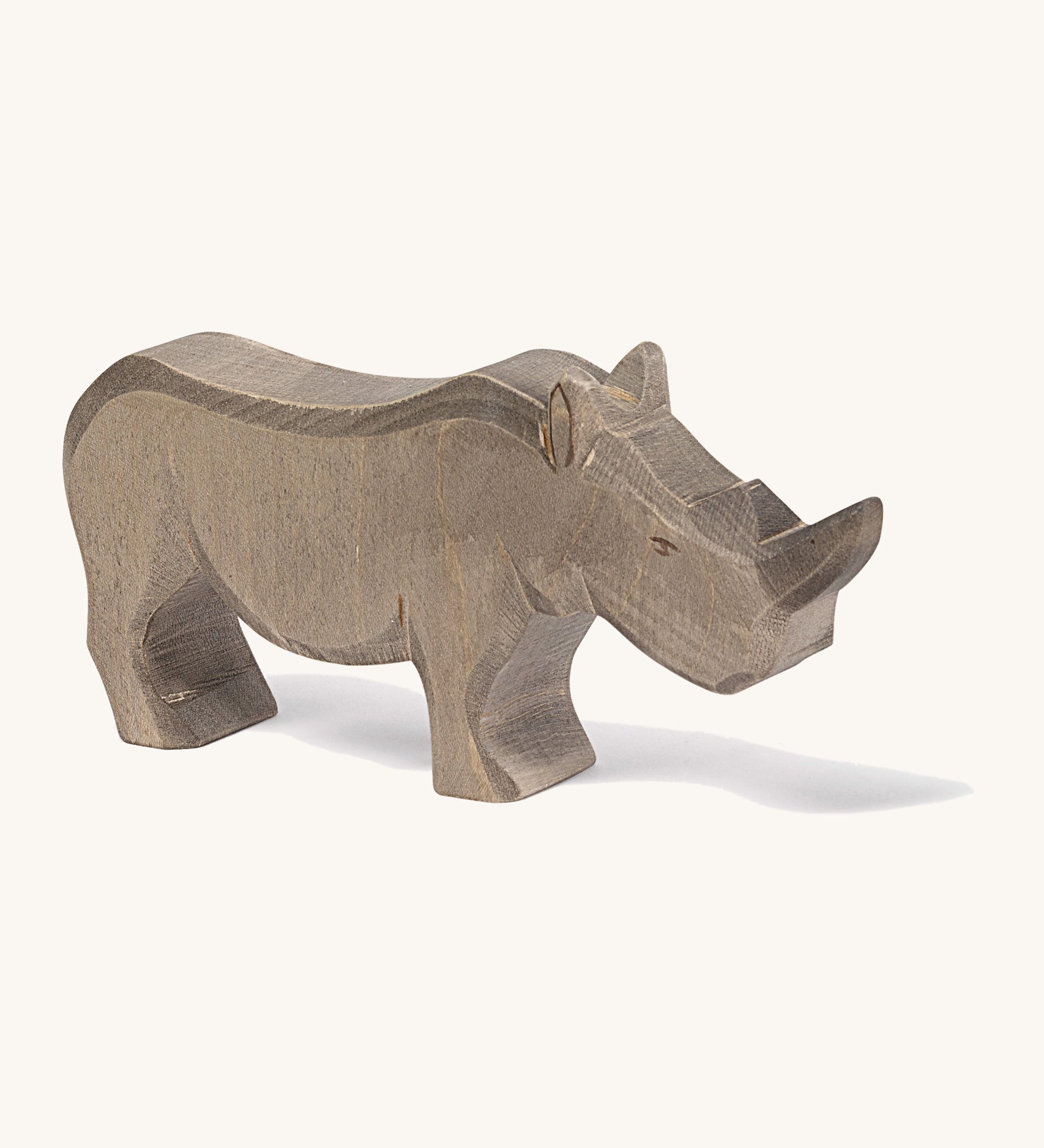 A wooden adult Ostheimer rhino figure on a cream background.