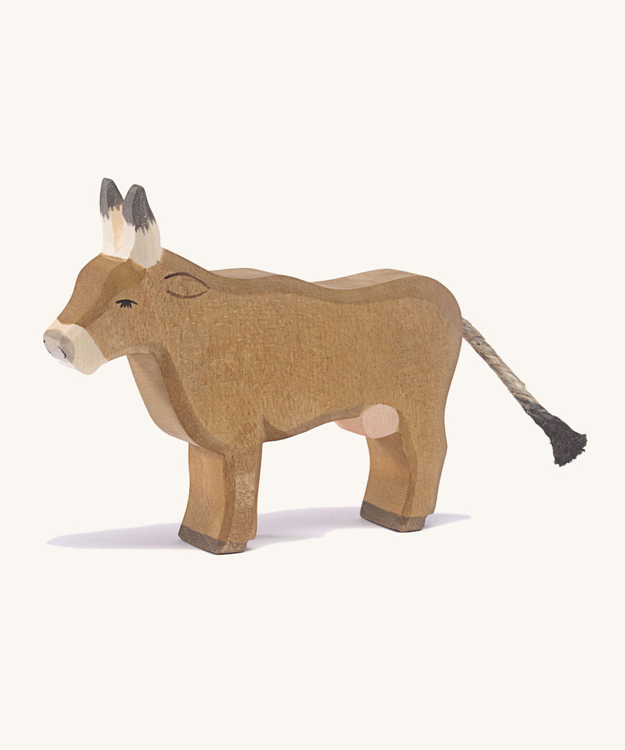 A wooden Ostheimer alp cow standing on a cream background.