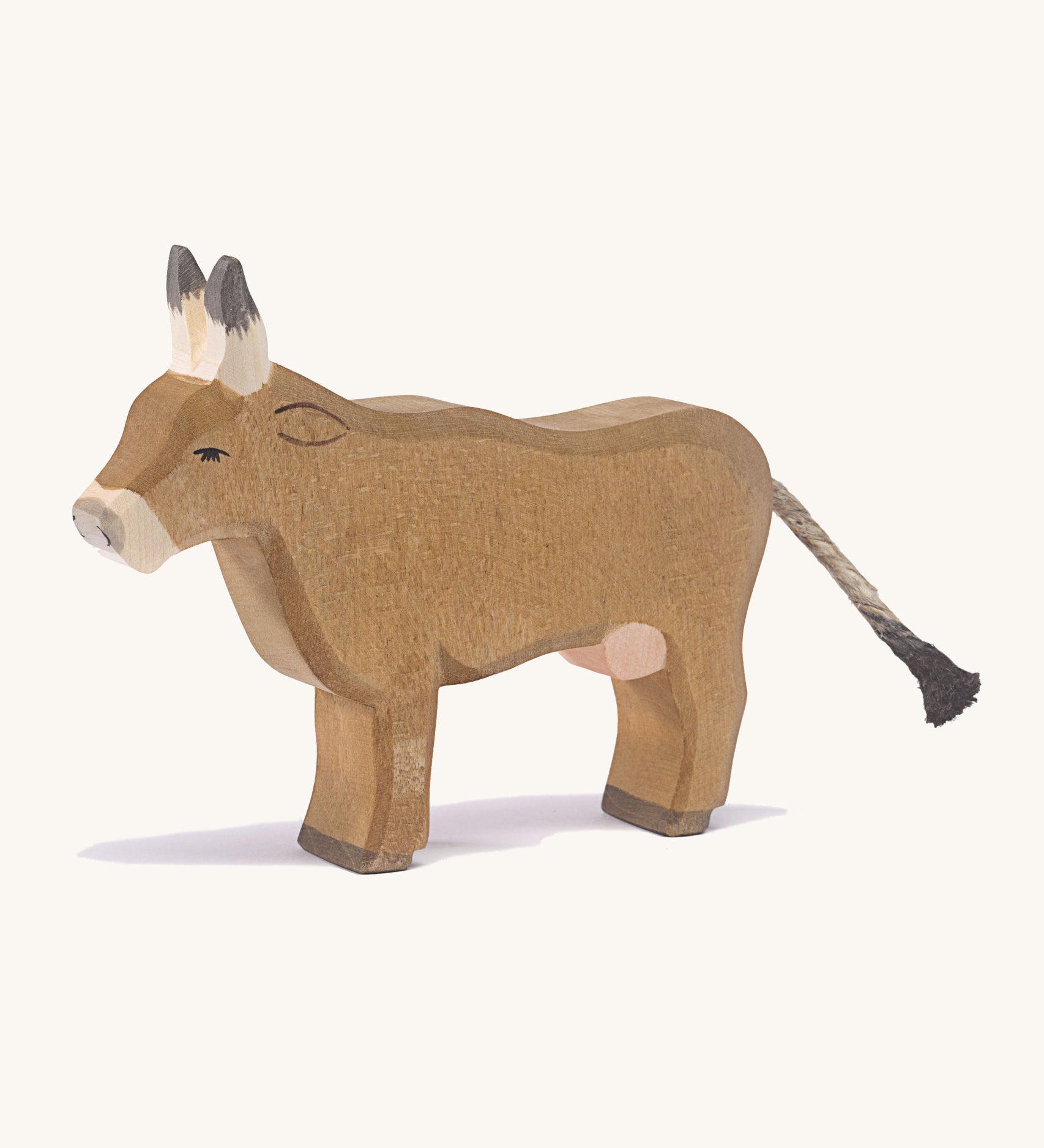 A wooden Ostheimer alp cow standing on a cream background.