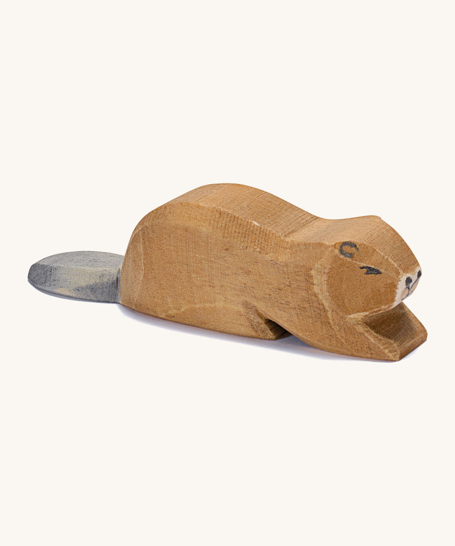 A wooden Ostheimer beaver lying down on a cream background.