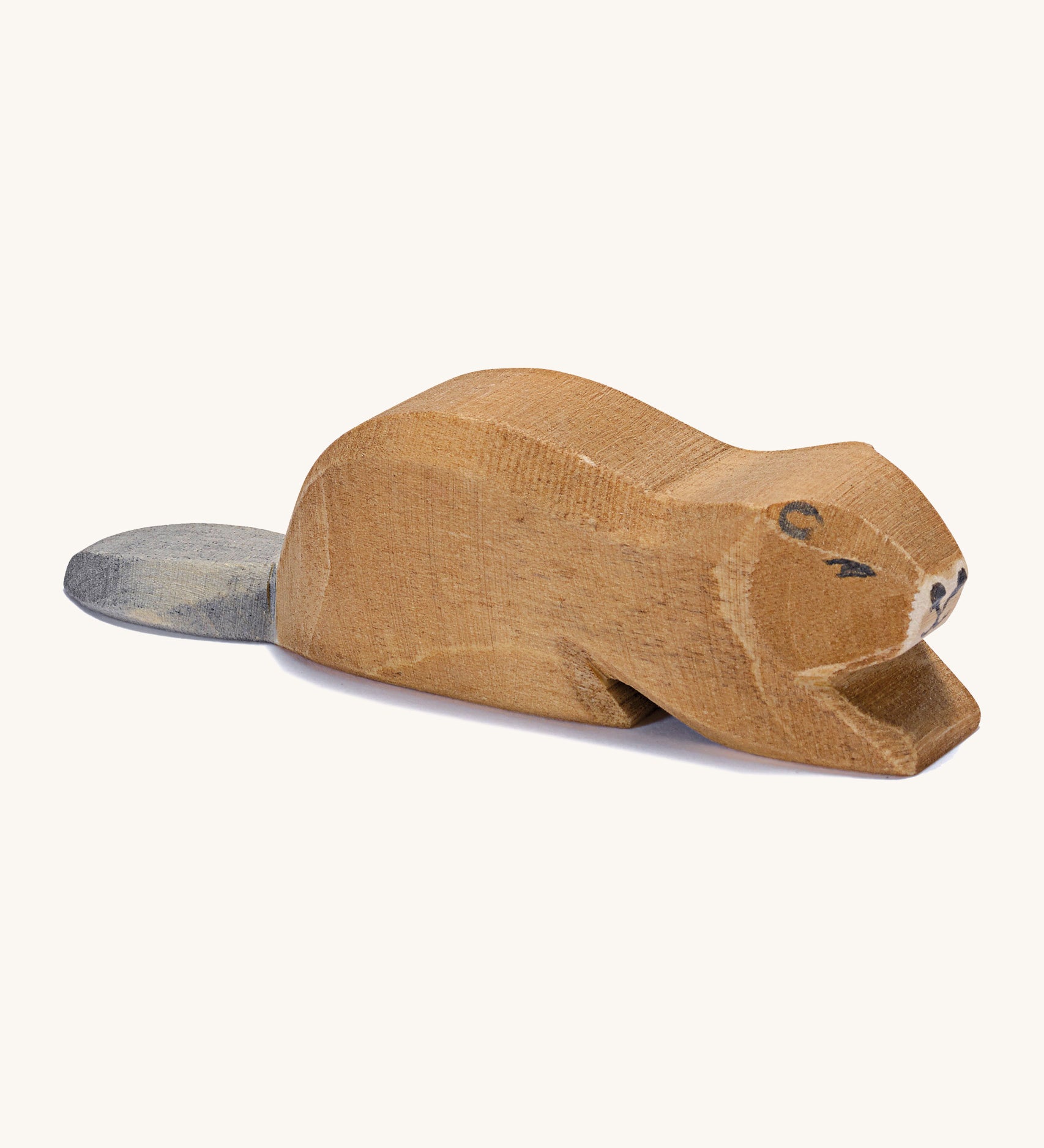 A wooden Ostheimer beaver lying down on a cream background.