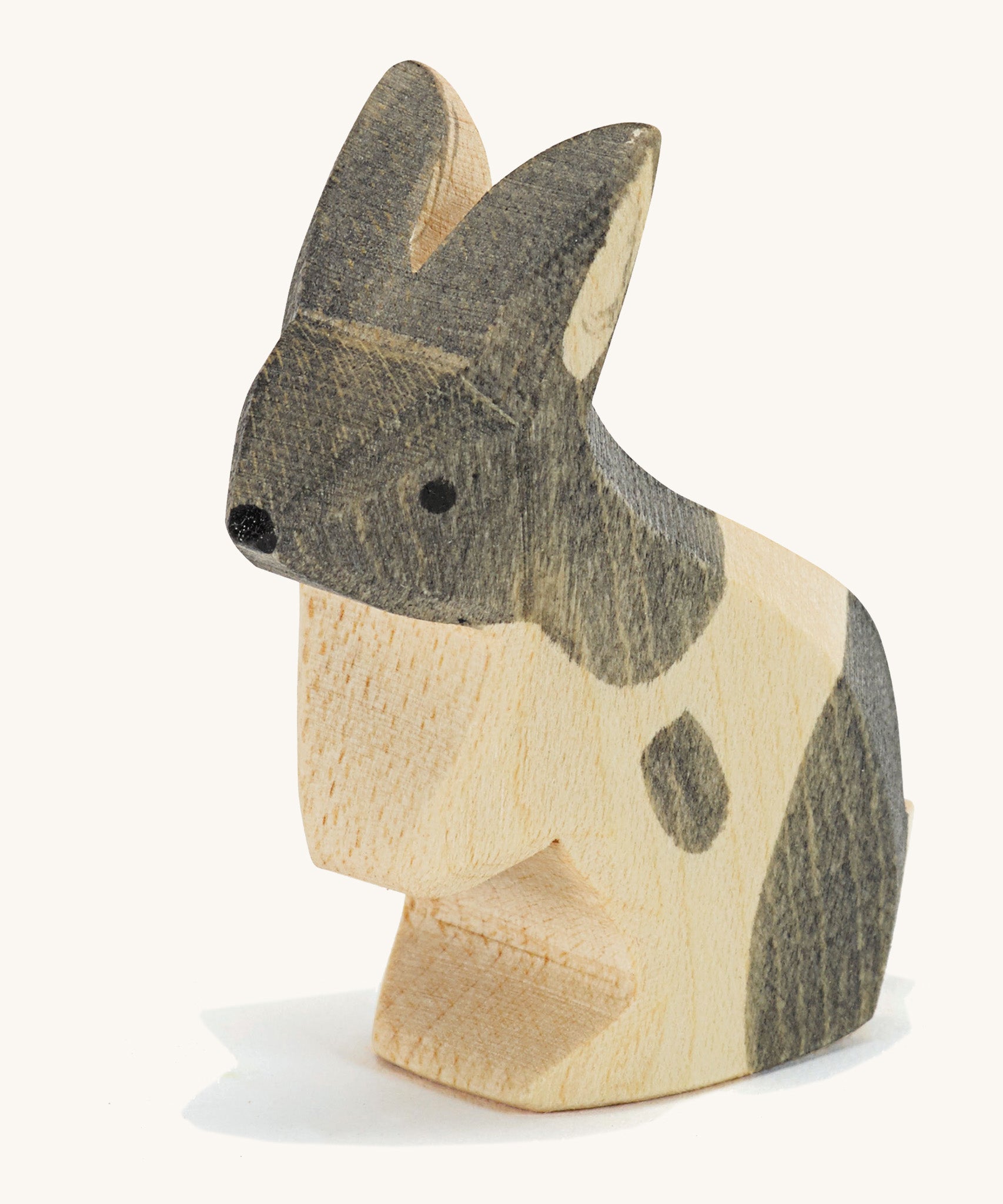 A wooden Ostheimer black and white standing rabbit figure on a cream background.