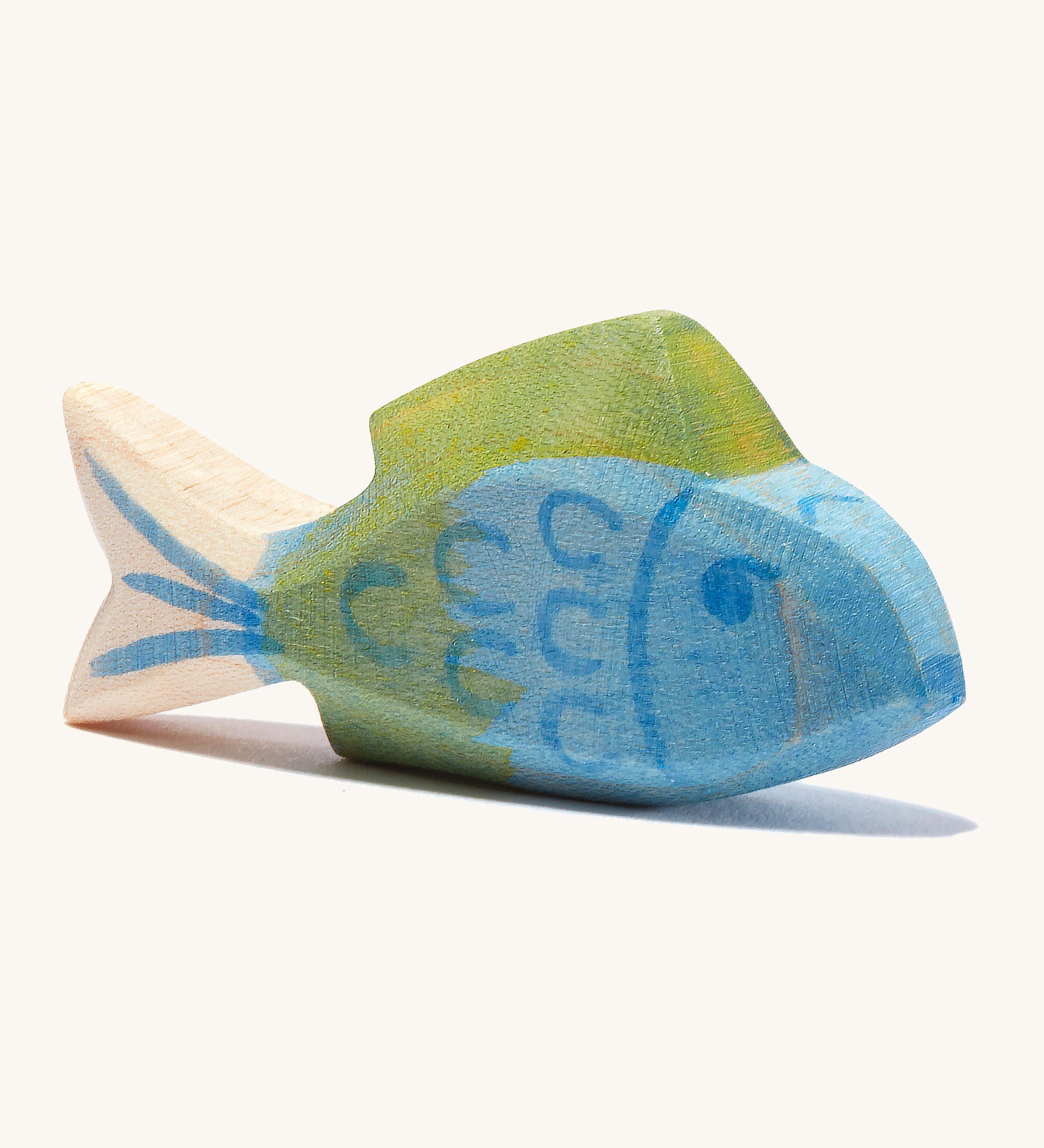 A blue wooden Ostheimer fish figure with green fins in a cream background.