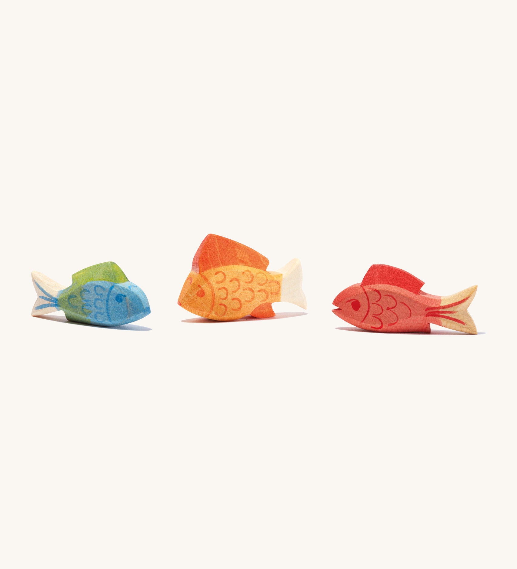 A blue, orange and red wooden Ostheimer fish figures on a cream background.