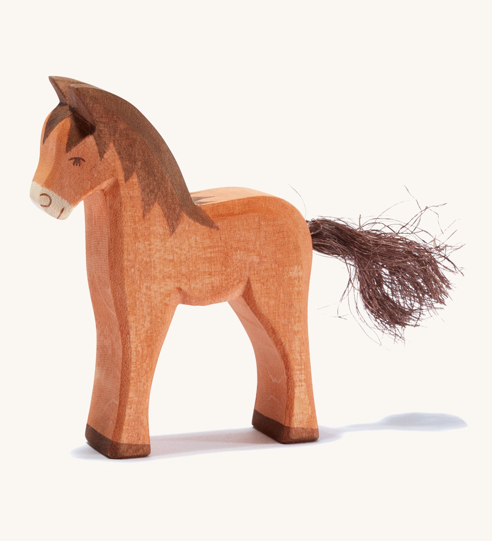 A brown wooden Ostheimer colt figure on a cream background.