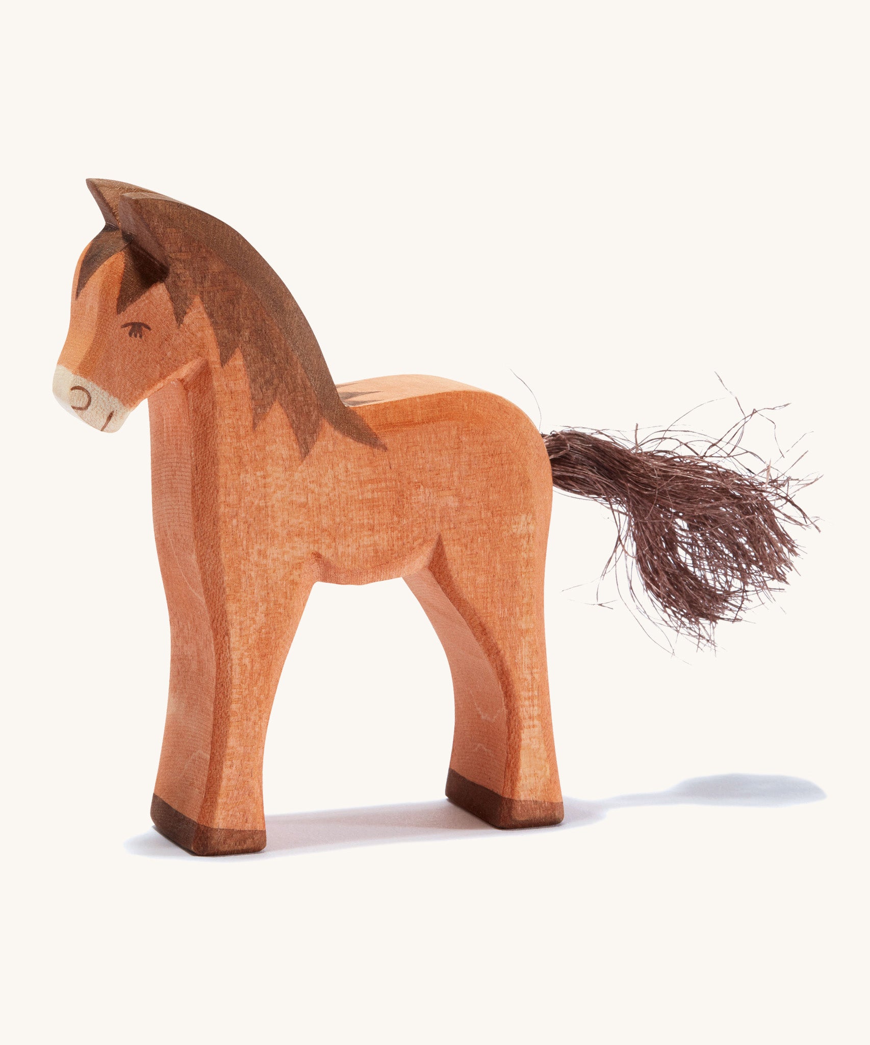 A brown wooden Ostheimer colt figure on a cream background.