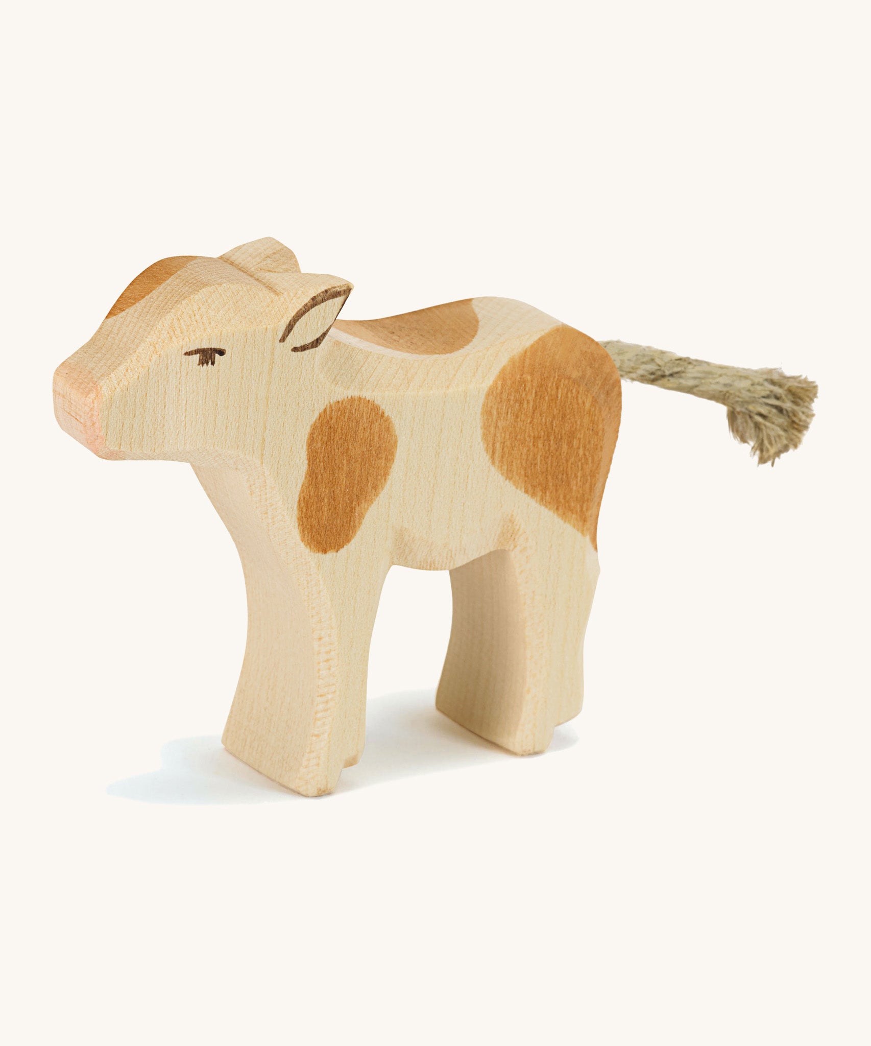 A wooden brown and white Ostheimer standing calf on a cream background.