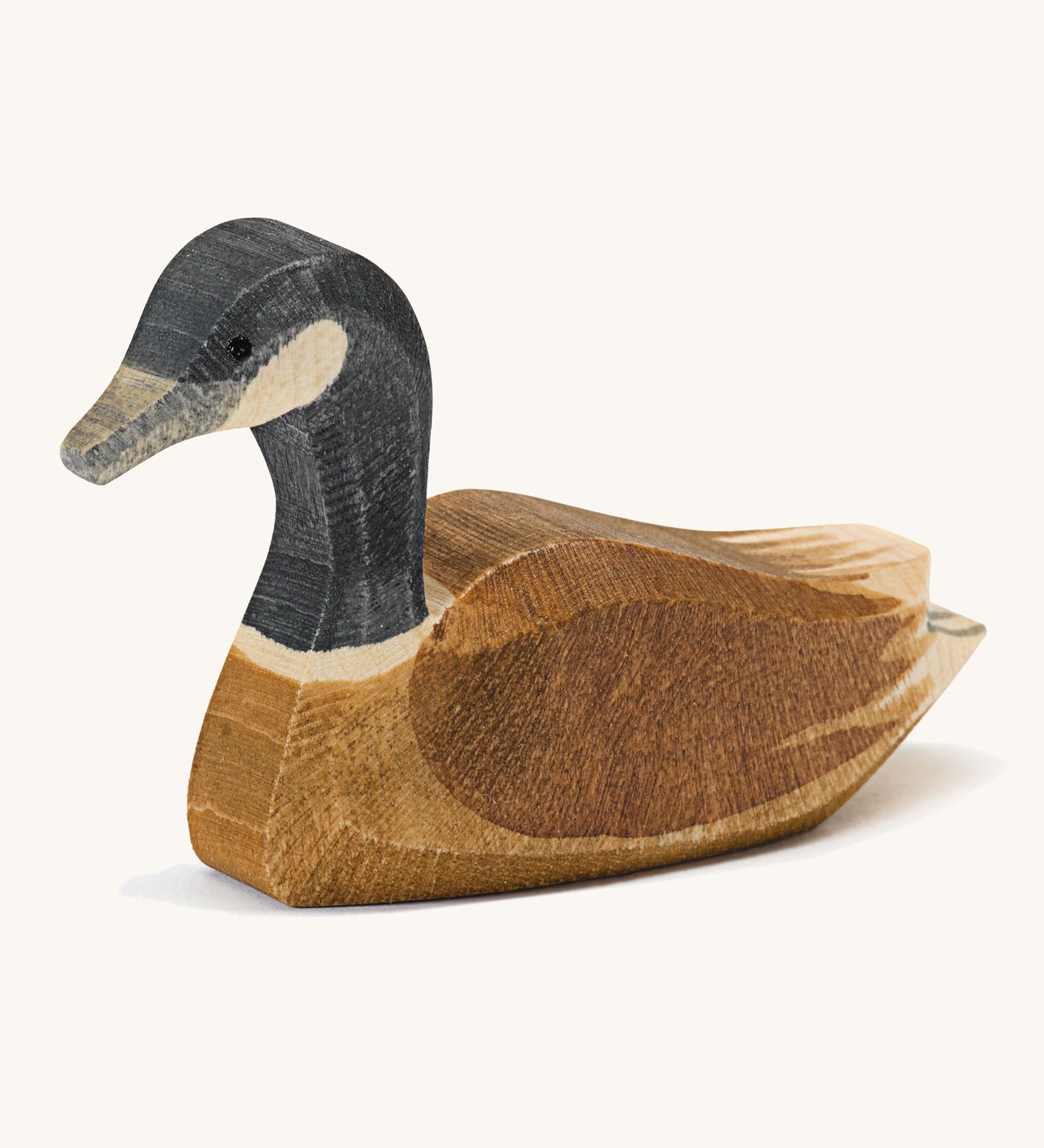 A wooden swimming Ostheimer Canadian goose on a cream background.