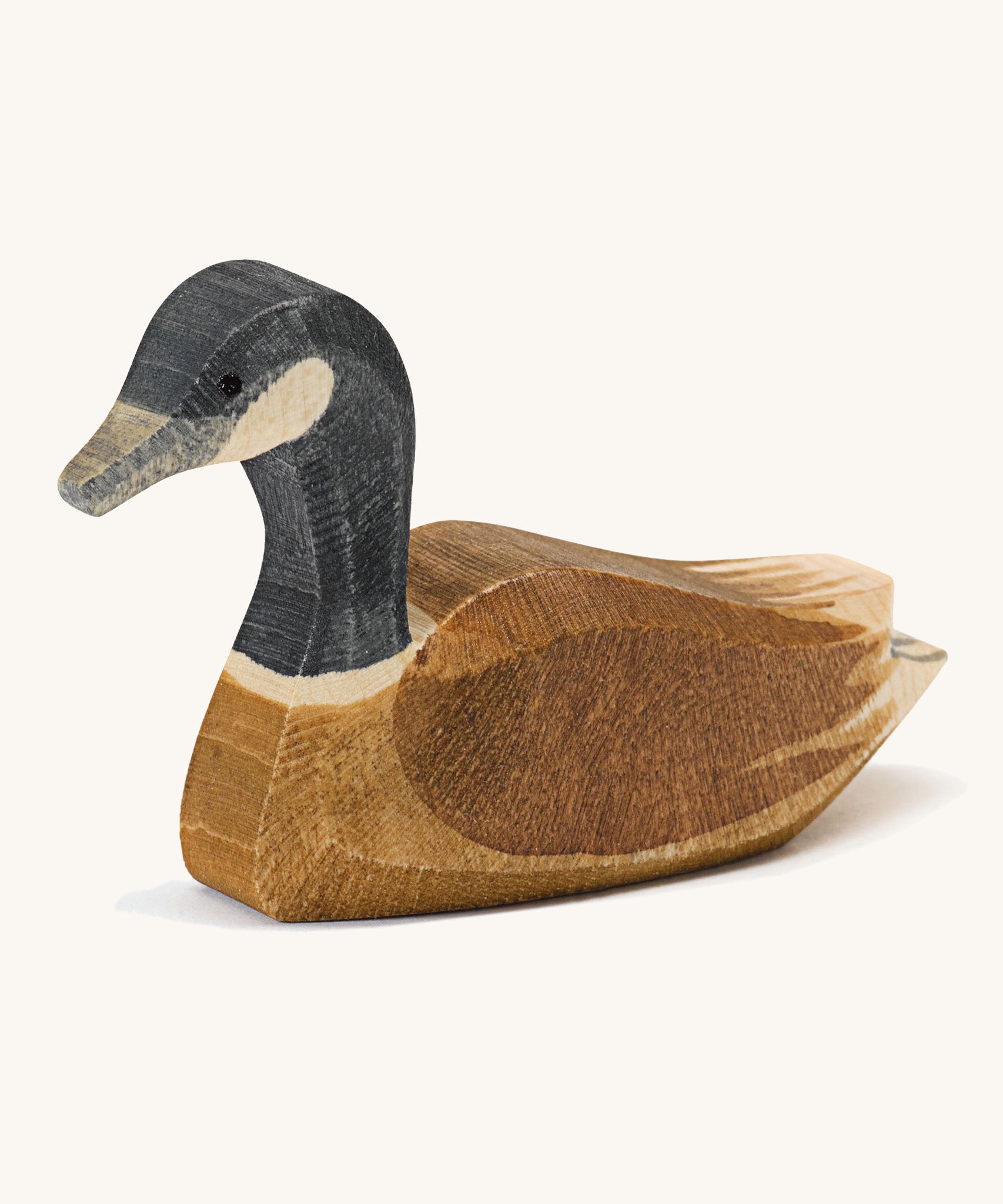 A wooden swimming Ostheimer Canadian goose on a cream background.