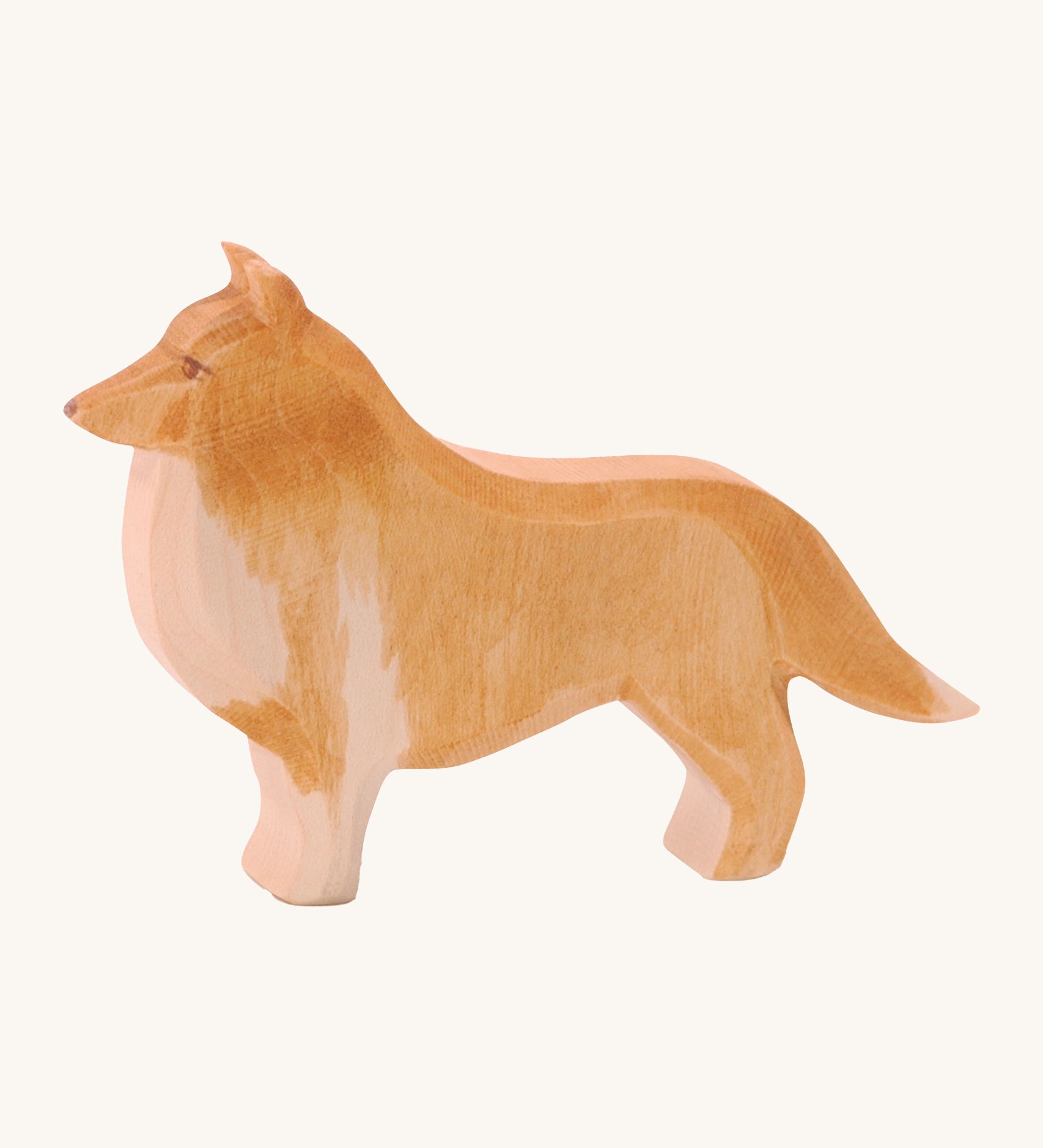 A wooden Ostheimer collie dog figure on a cream background.