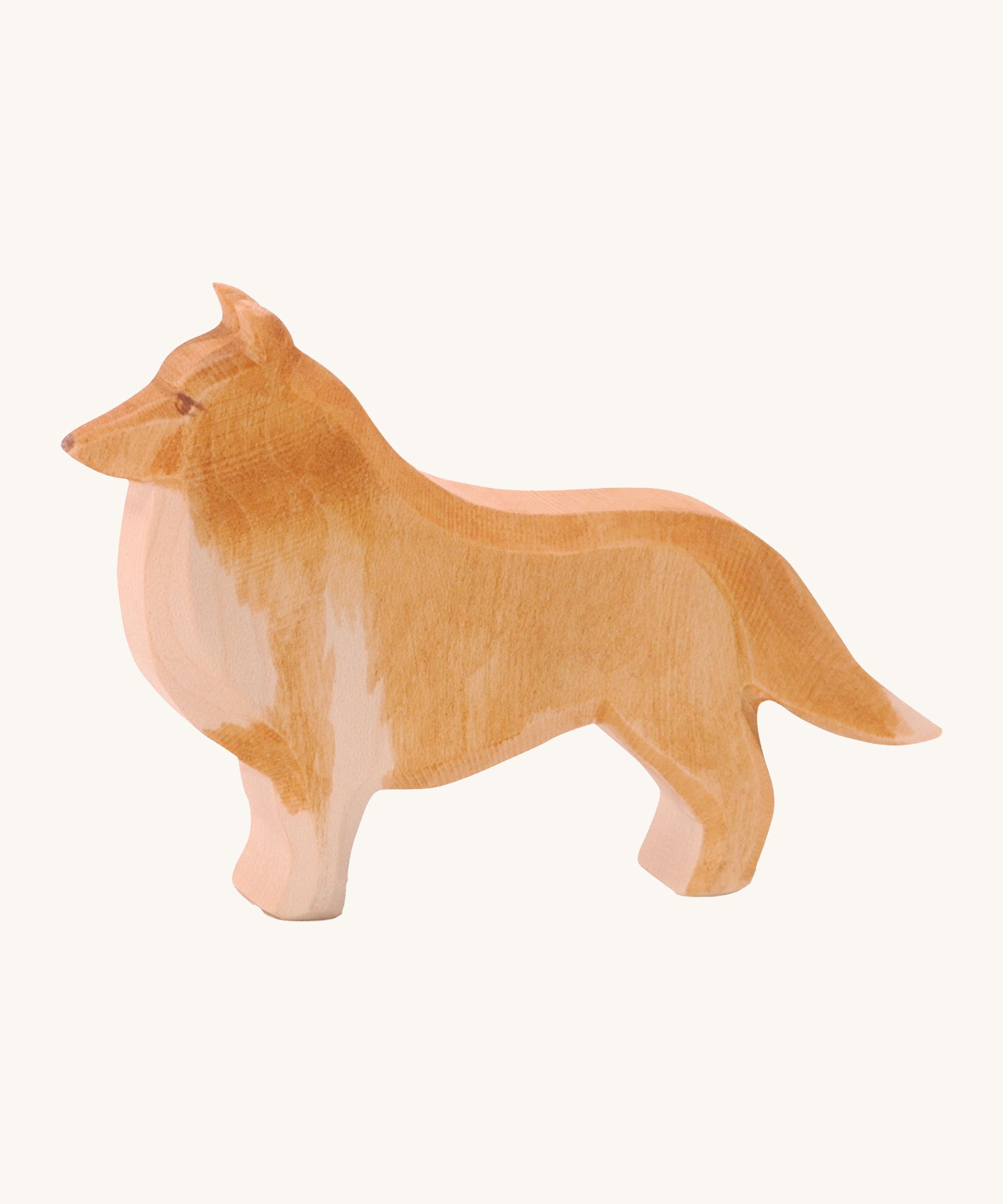 A wooden Ostheimer collie dog figure on a cream background.