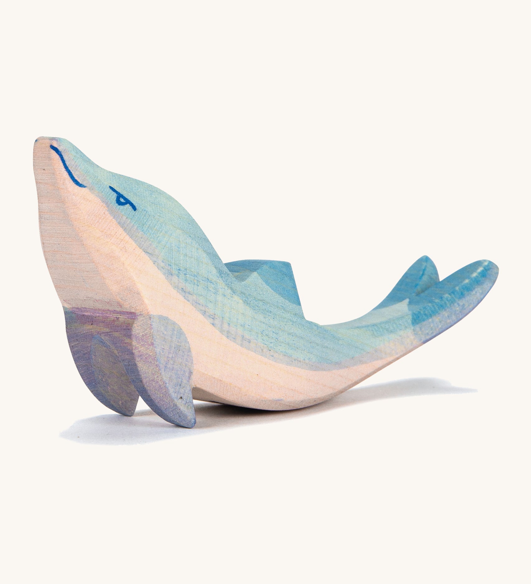 A wooden Ostheimer dolphin figure with its head held high on a cream background.