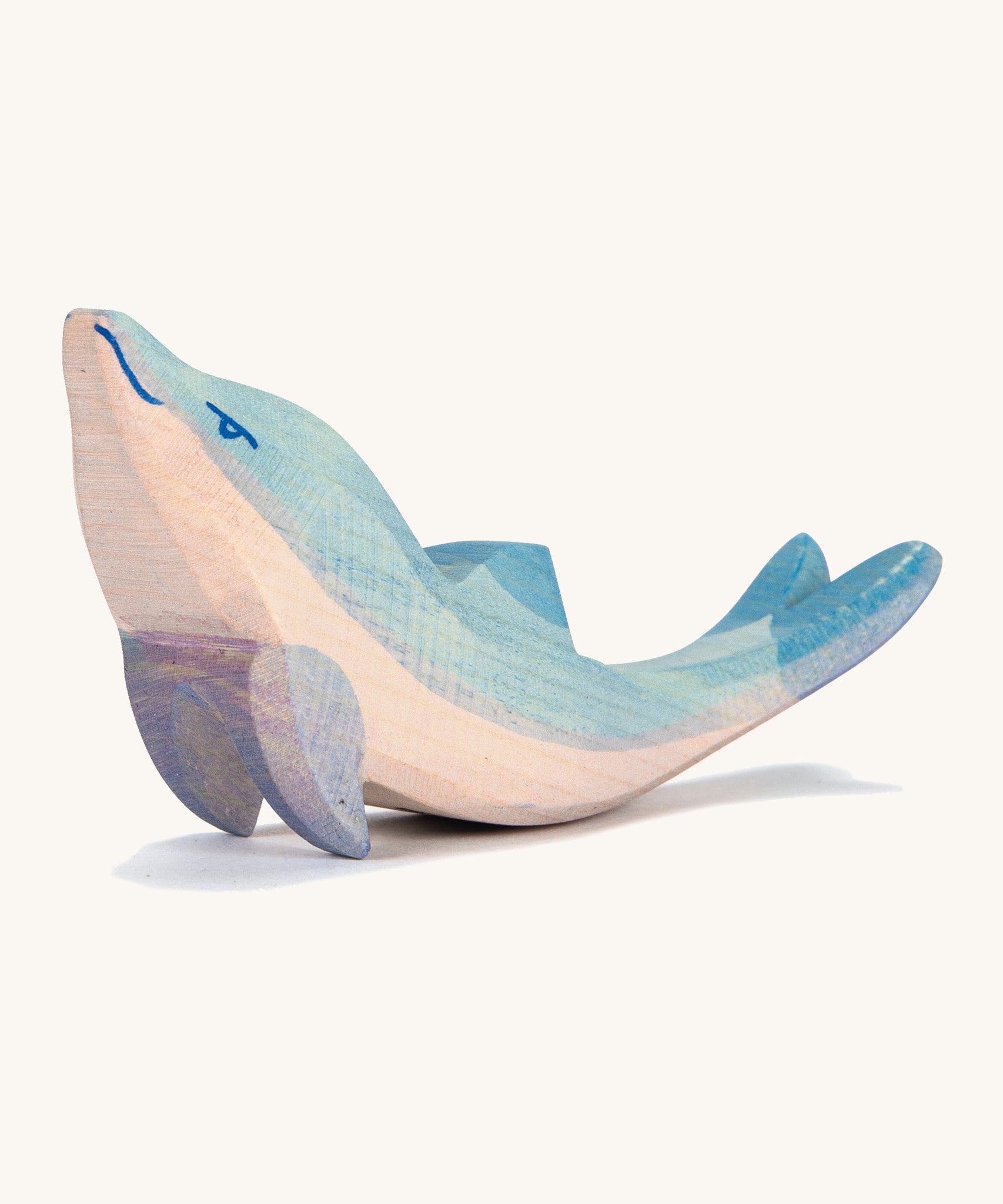 A wooden Ostheimer dolphin figure with its head held high on a cream background.