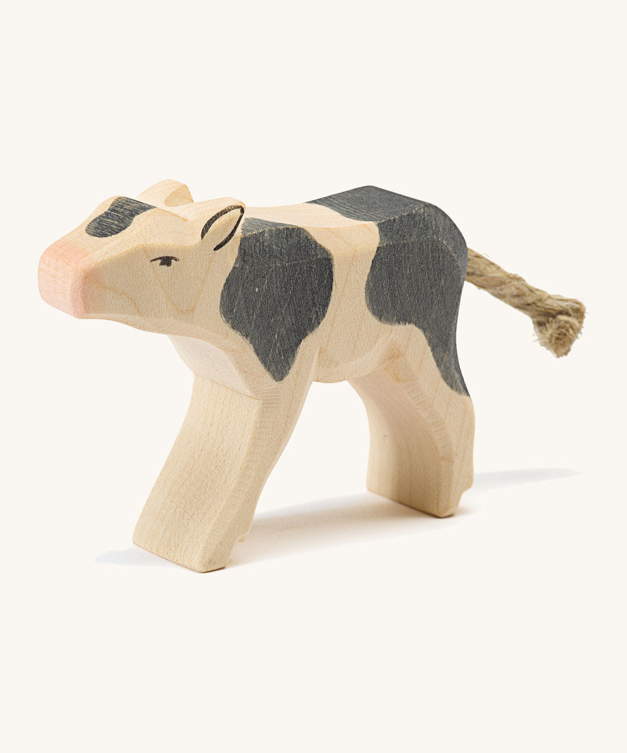 A wooden black and white Ostheimer drinking calf figure on a cream background.