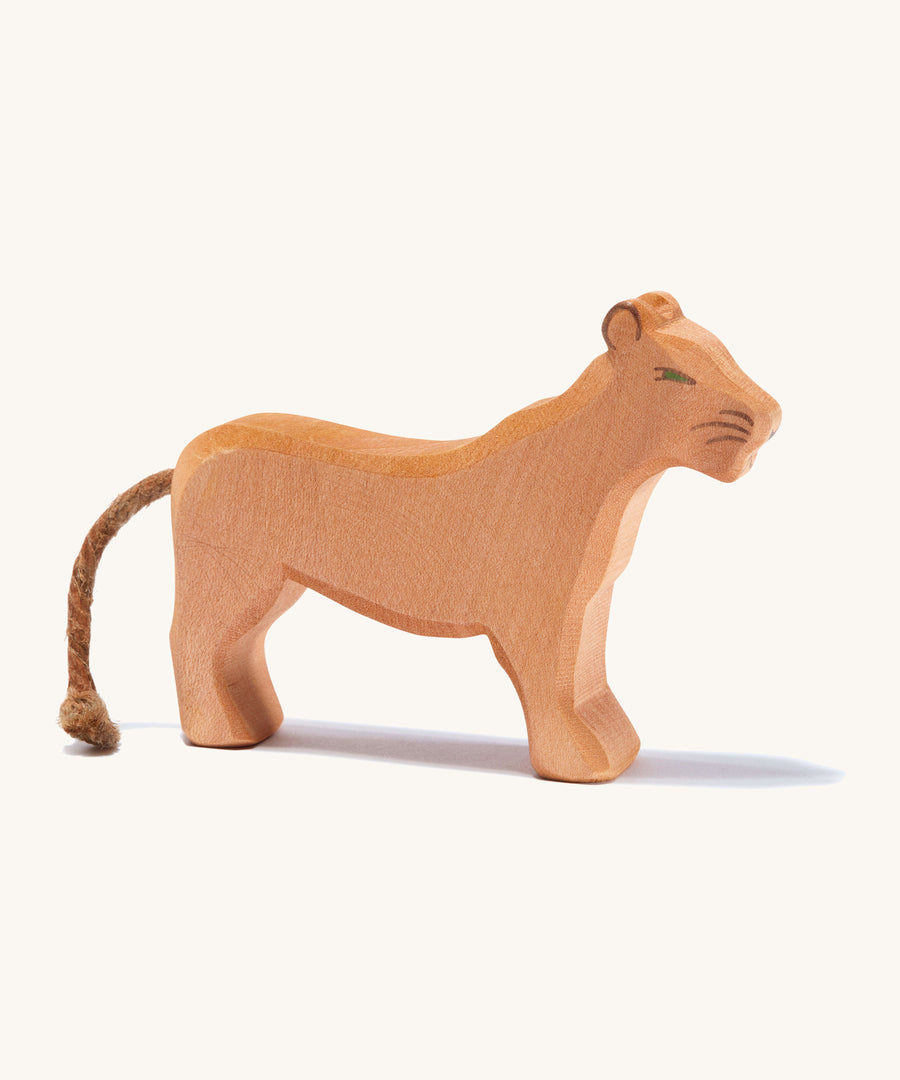 A wooden female Ostheimer lion figure on a cream background.