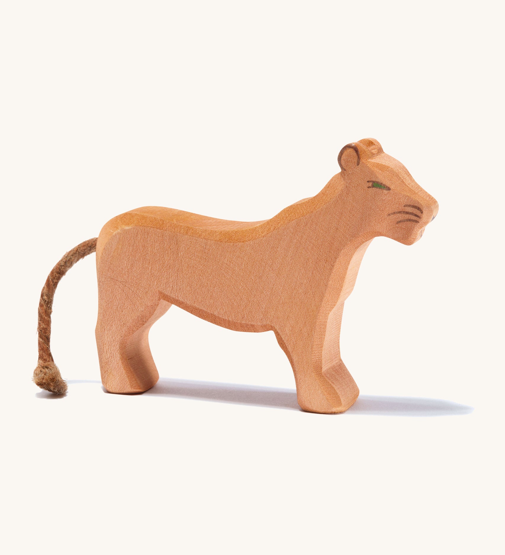 A wooden female Ostheimer lion figure on a cream background.