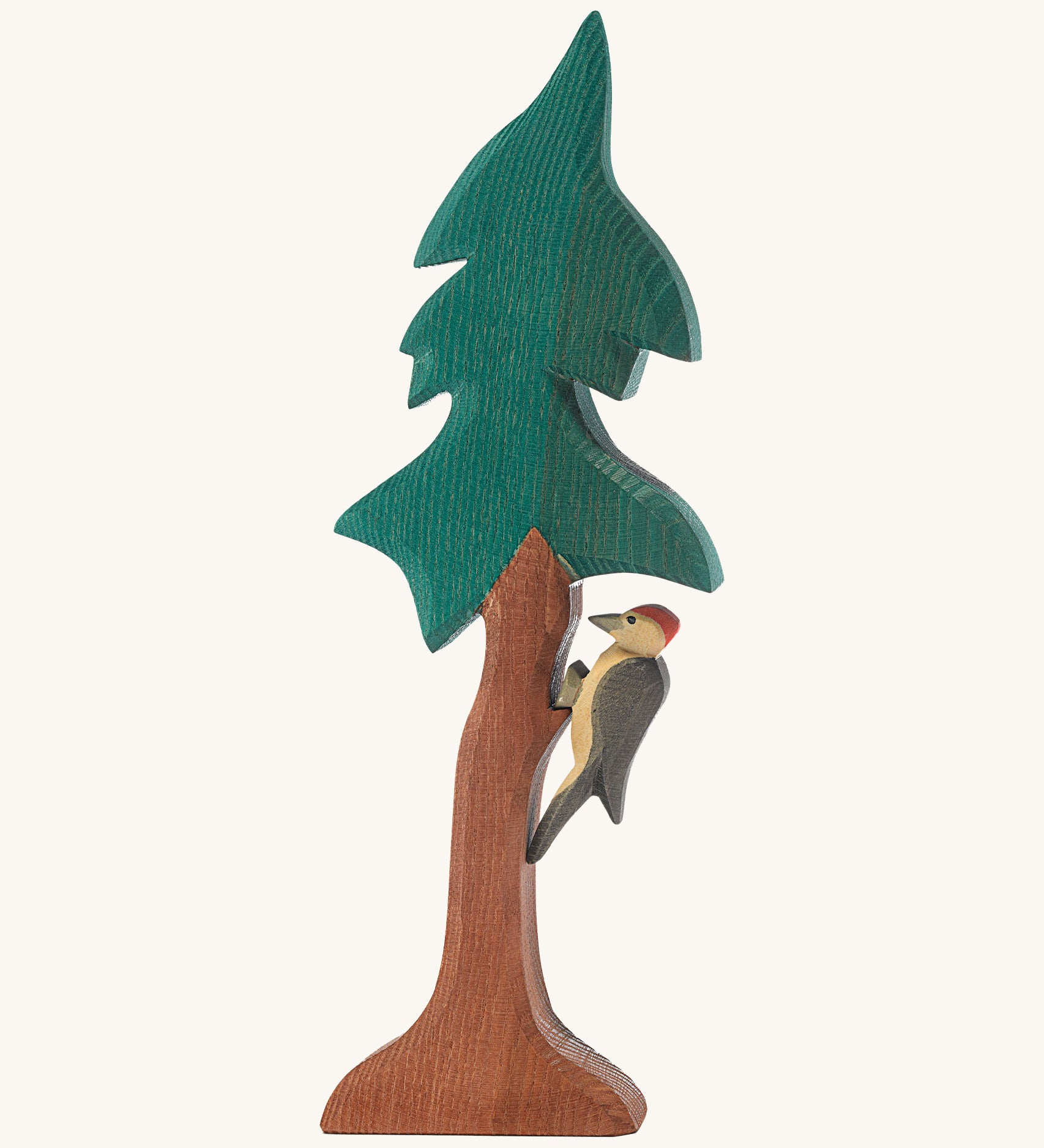 A wooden Ostheimer fir tree with a wooden Ostheimer woodpecker perched on the tree trunk on a cream background.