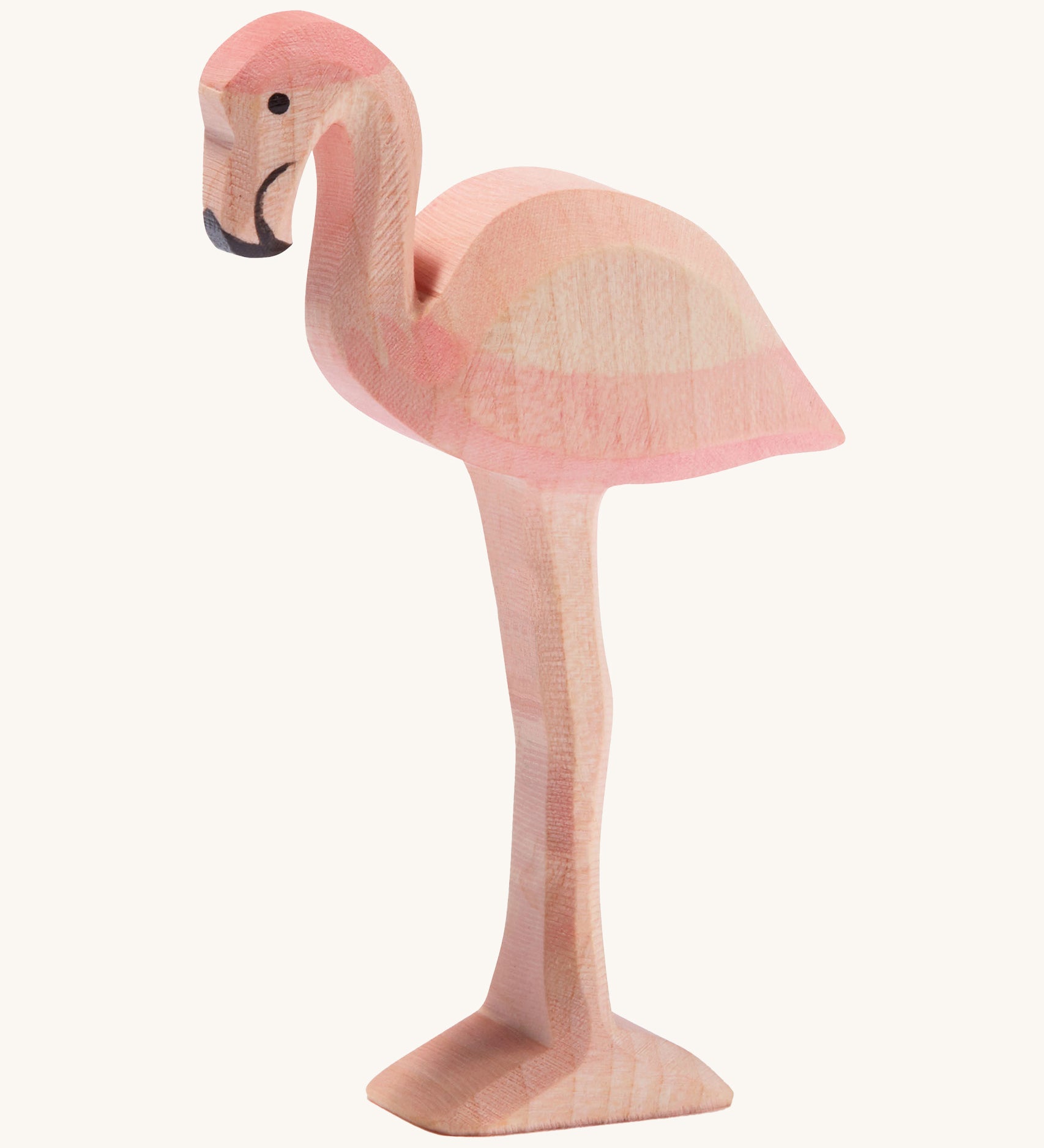 Ostheimer wooden flamingo in pink with black beak on a cream background.