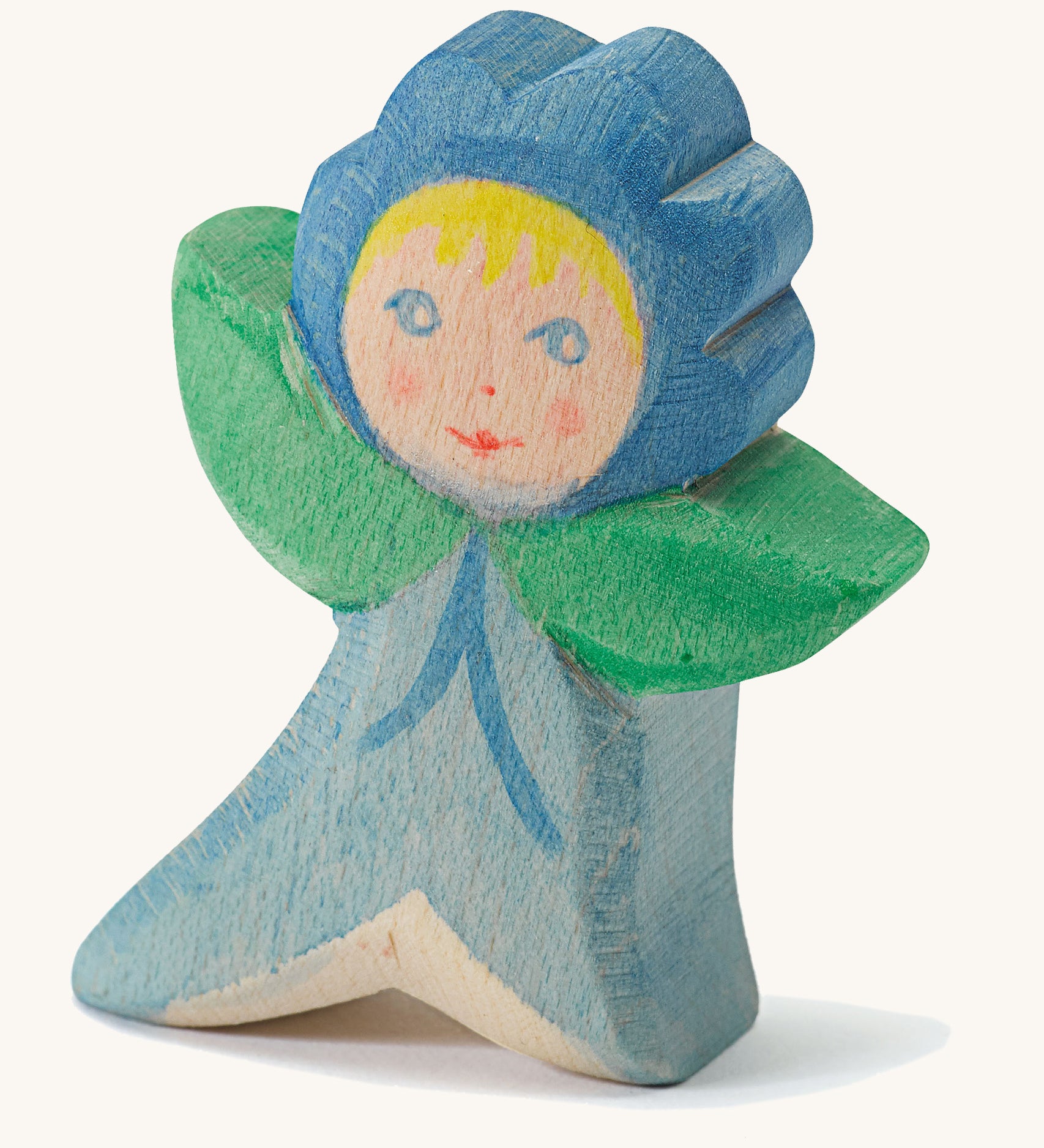 A wooden Ostheimer forget me not figure wearing a blue outfit and a matching blue hat on a cream background.