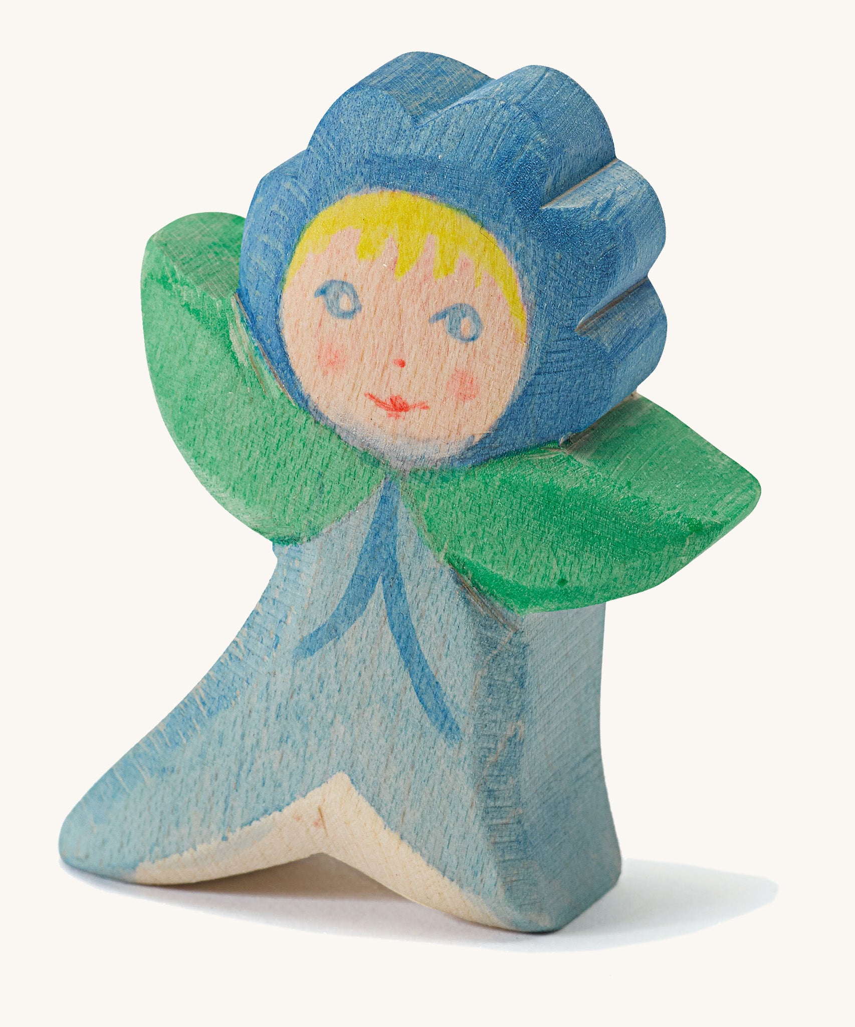 A wooden Ostheimer forget me not figure wearing a blue outfit and a matching blue hat on a cream background.