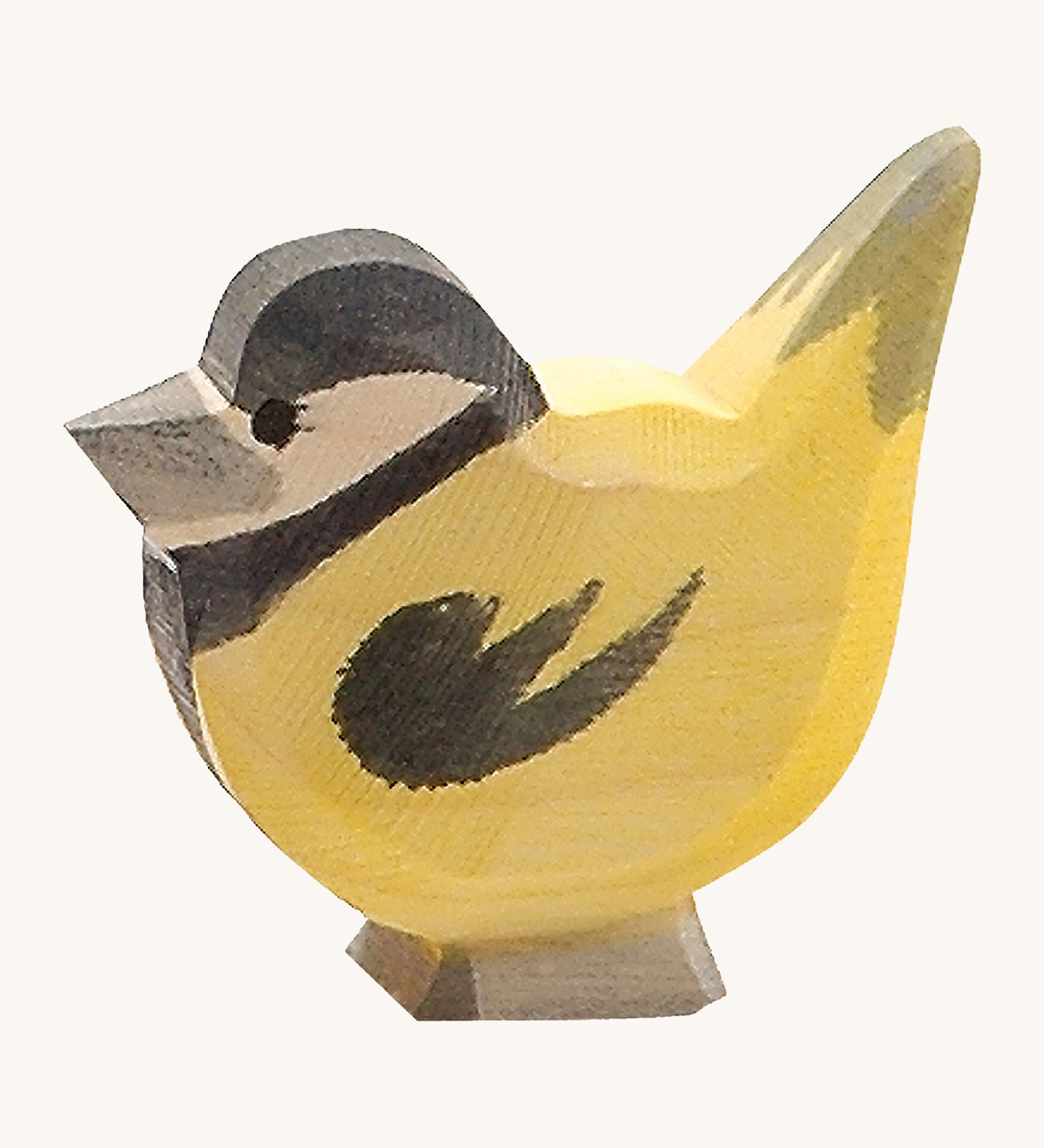 A wooden Ostheimer goldfinch bird figure on a cream background