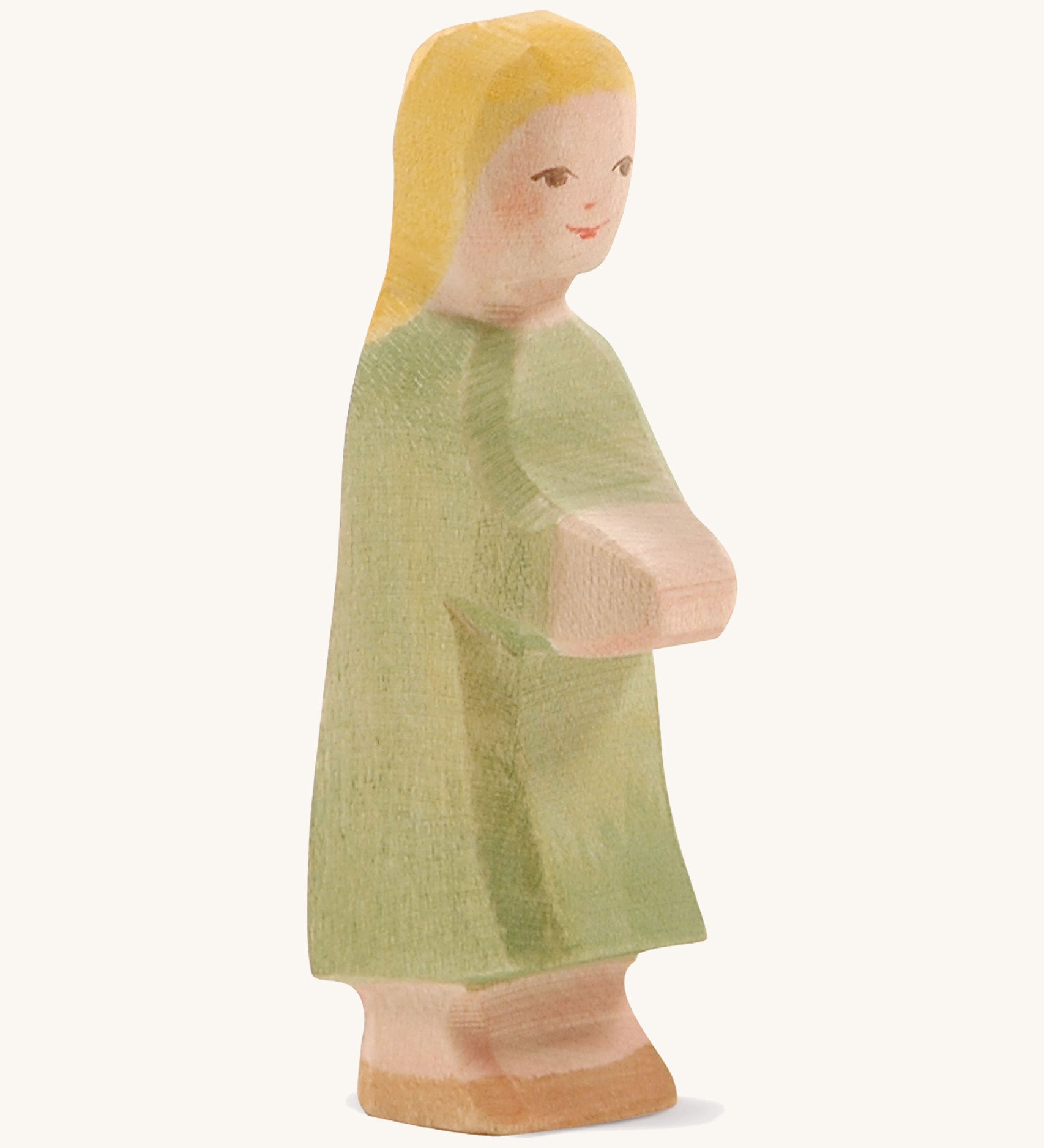 A wooden Ostheimer wooden Gretel with blonde hair figure wearing a green dress on a cream background.