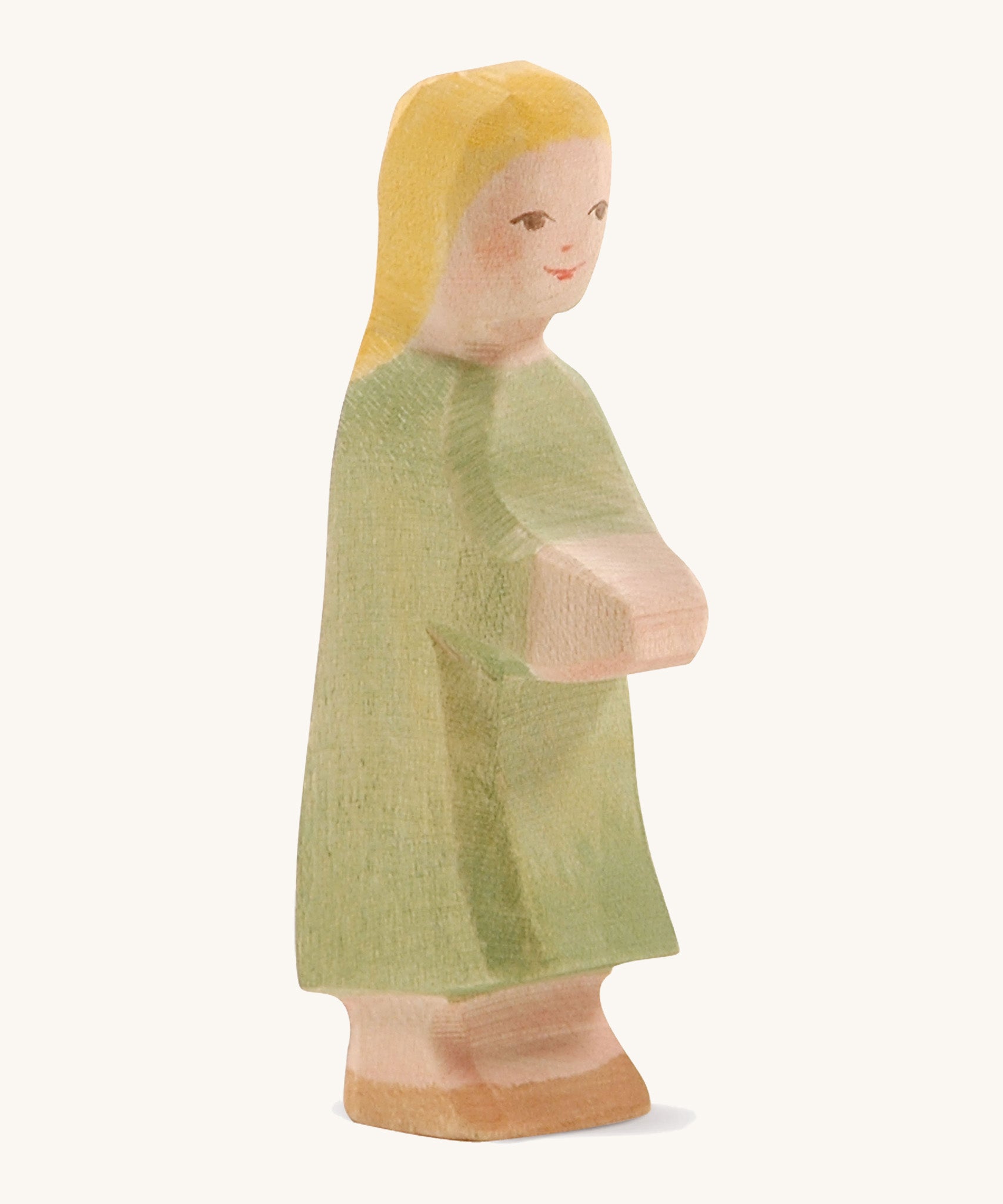 A wooden Ostheimer wooden Gretel with blonde hair figure wearing a green dress on a cream background.