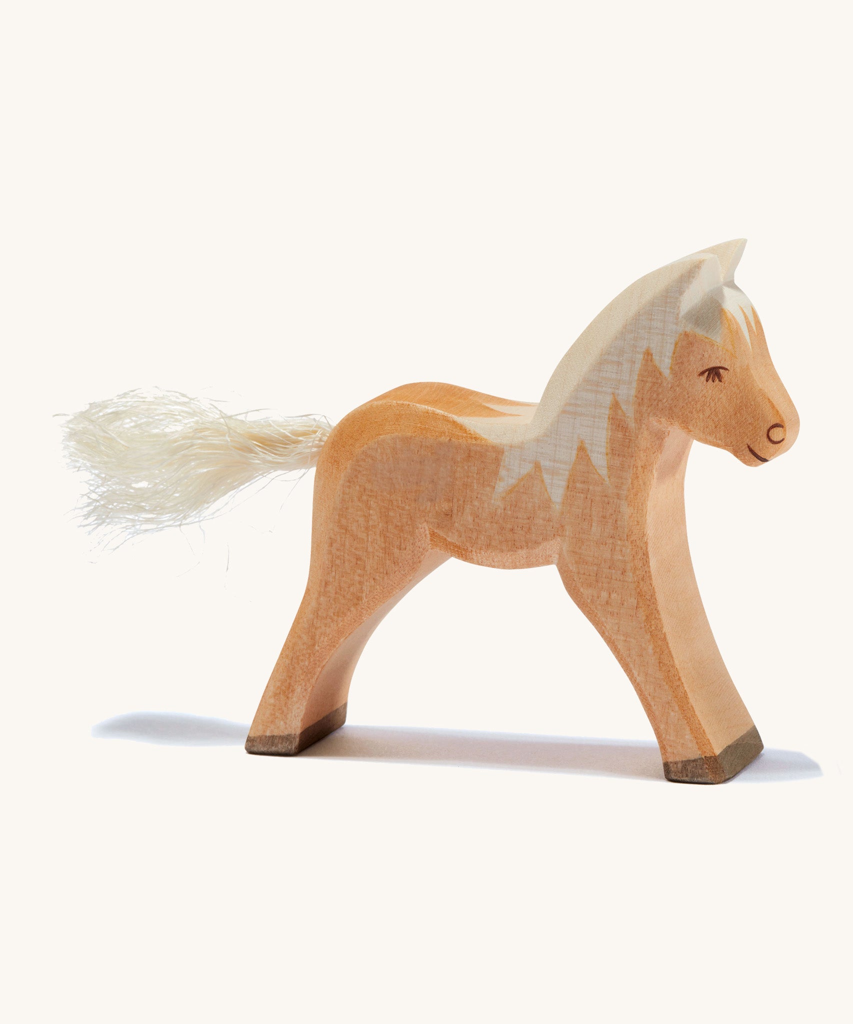 A brown wooden haflinger Ostheimer colt figure on a cream background.