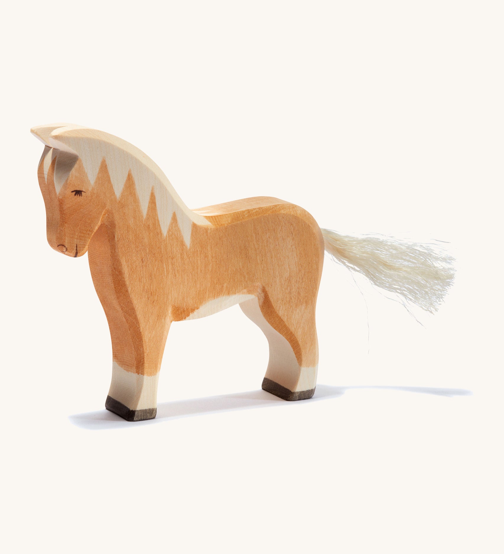 A brown wooden haflinger Ostheimer horse figure on a cream background.