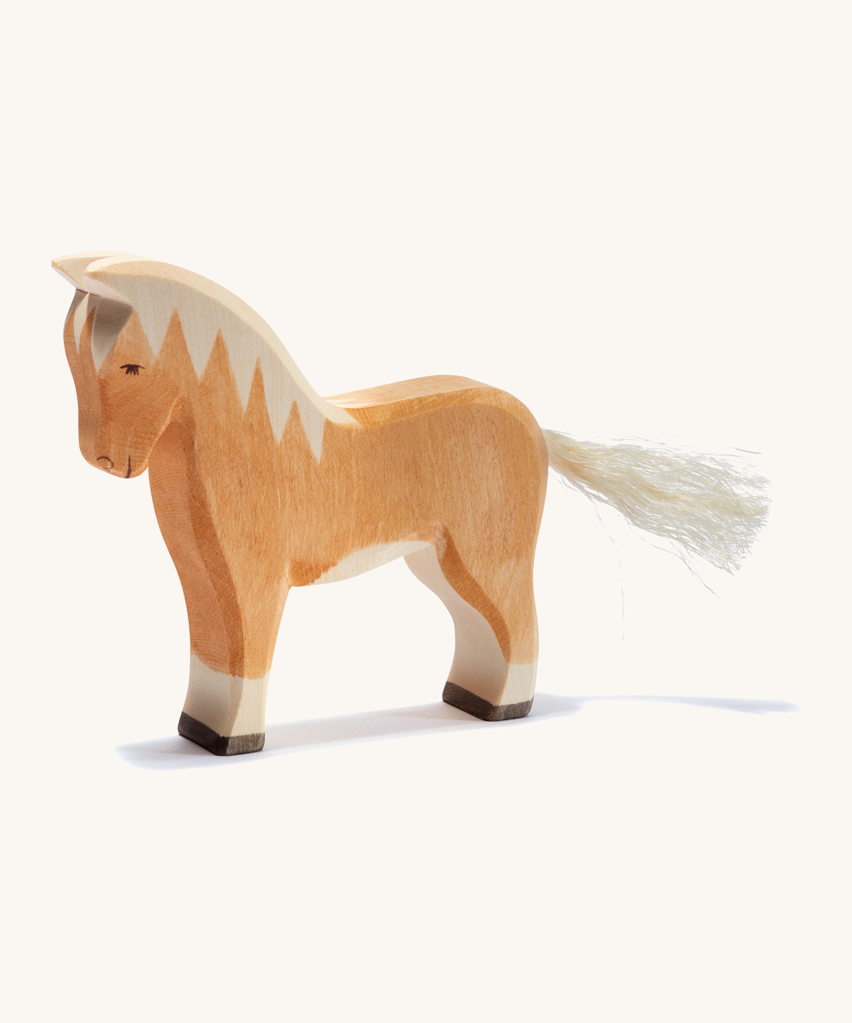 A brown wooden haflinger Ostheimer horse figure on a cream background.