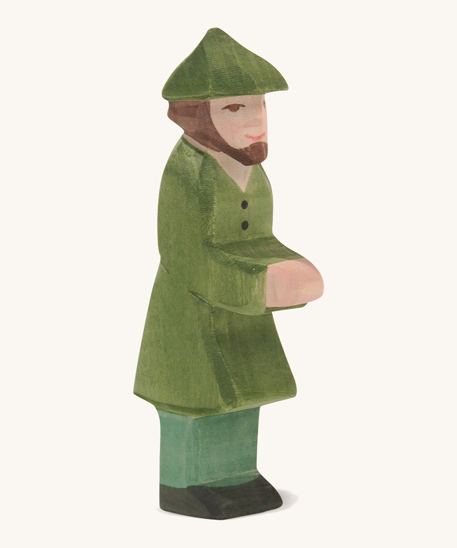 A wooden Ostheimer huntsman figure wearing a green coat and a green hat on a cream background.