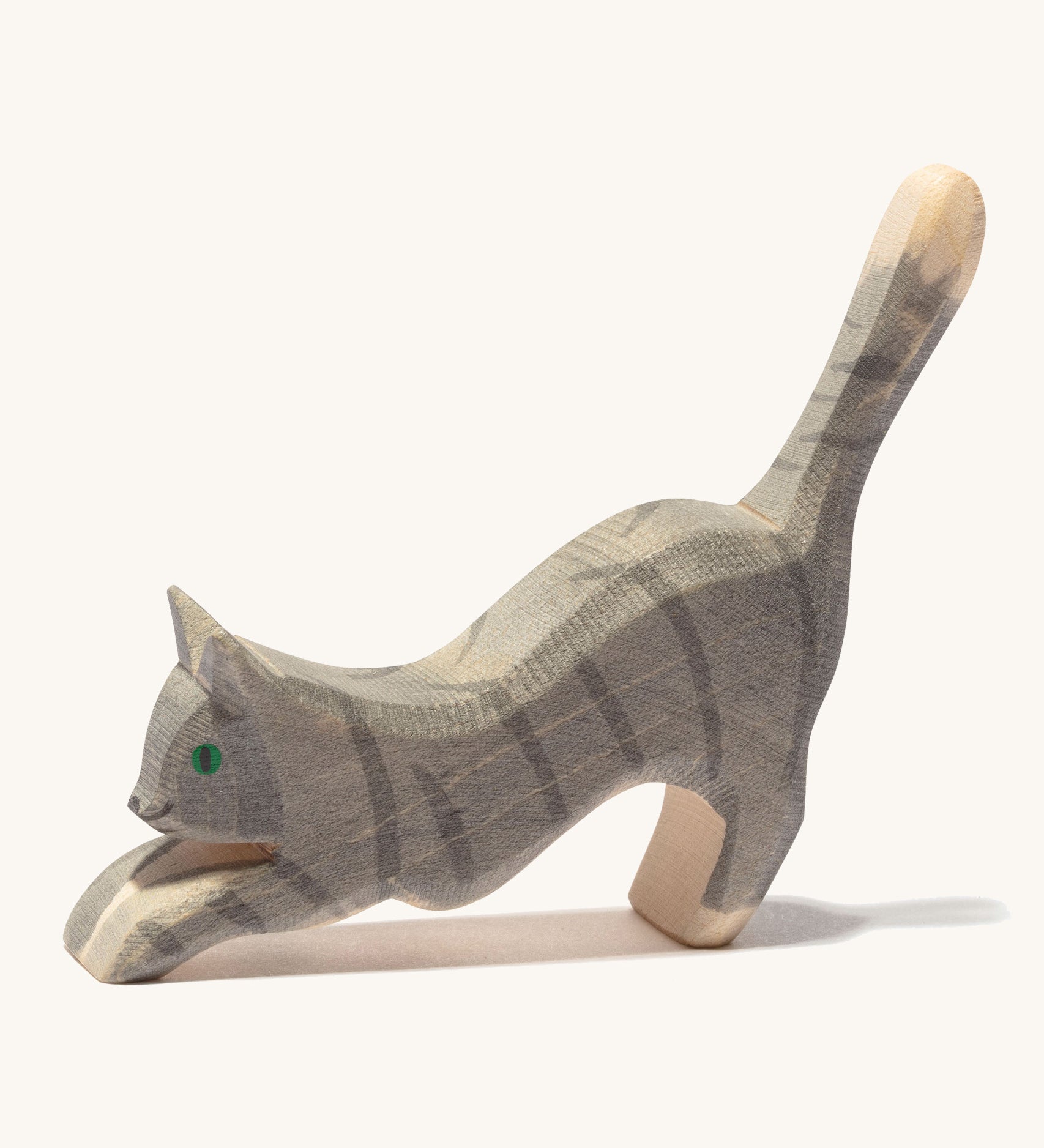 A grey striped wooden Ostheimer jumping cat figure on a cream background.