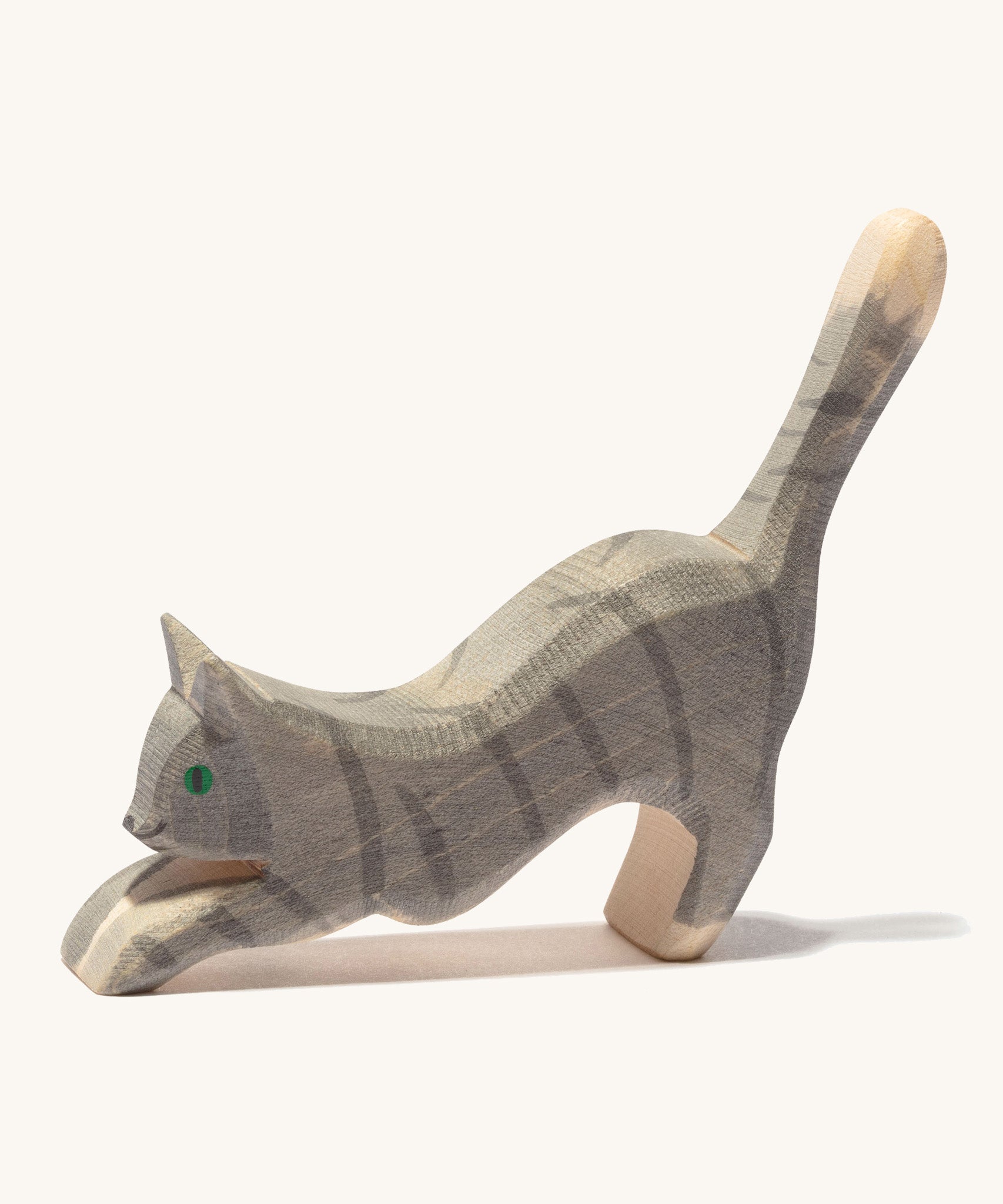 A grey striped wooden Ostheimer jumping cat figure on a cream background.