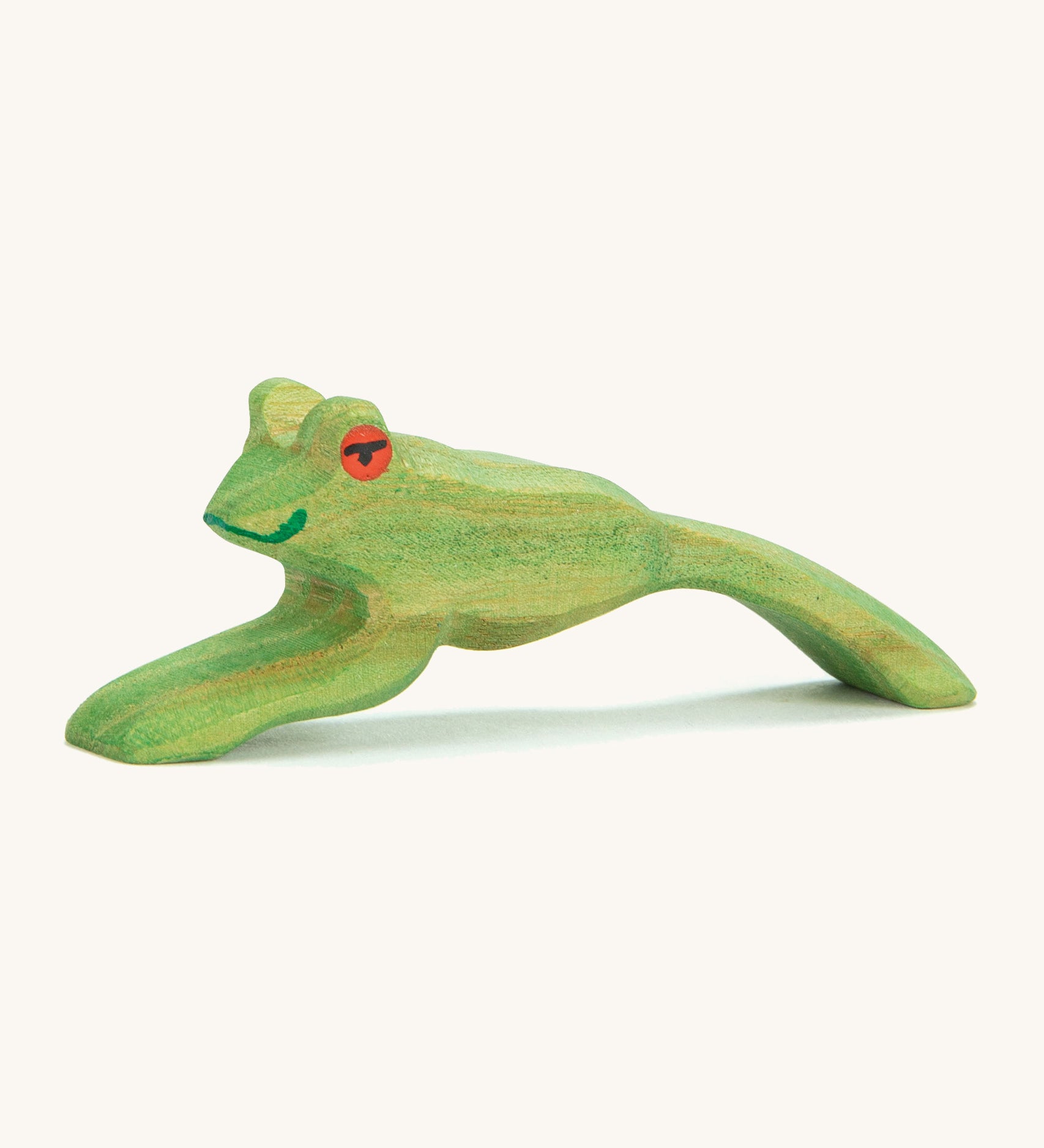 A green wooden Ostheimer jumping frog figure on a cream background.