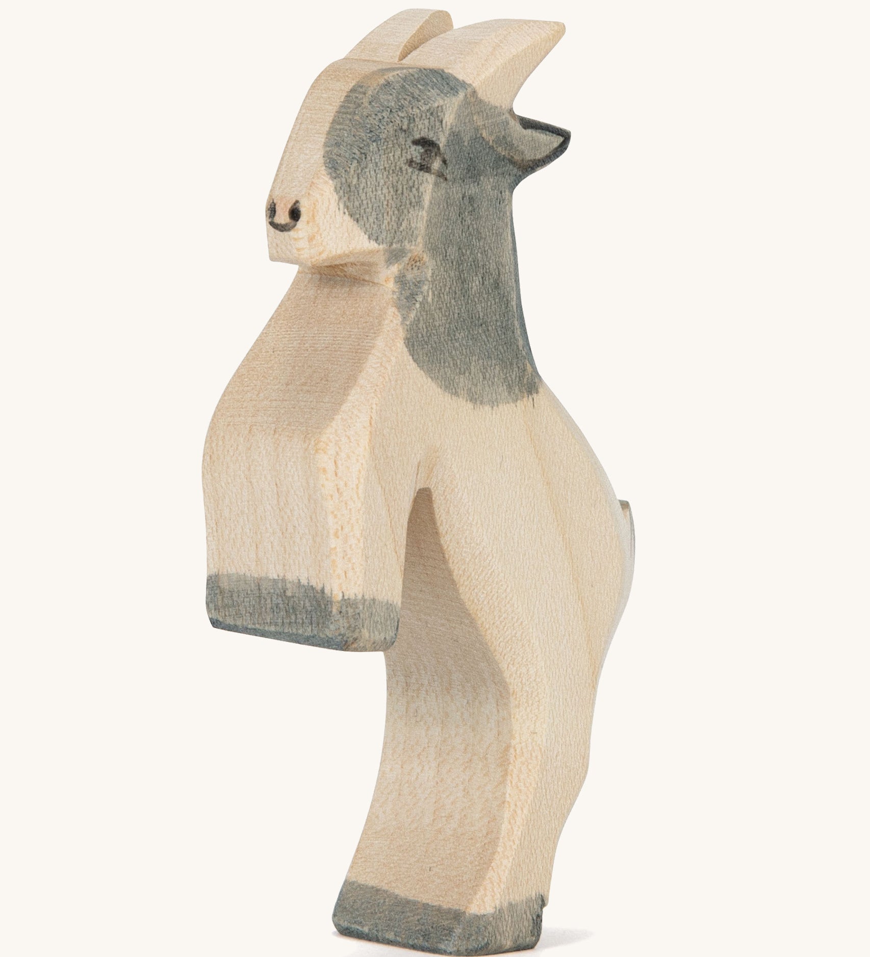 A grey and white wooden Ostheimer jumping goat figure on a cream background.